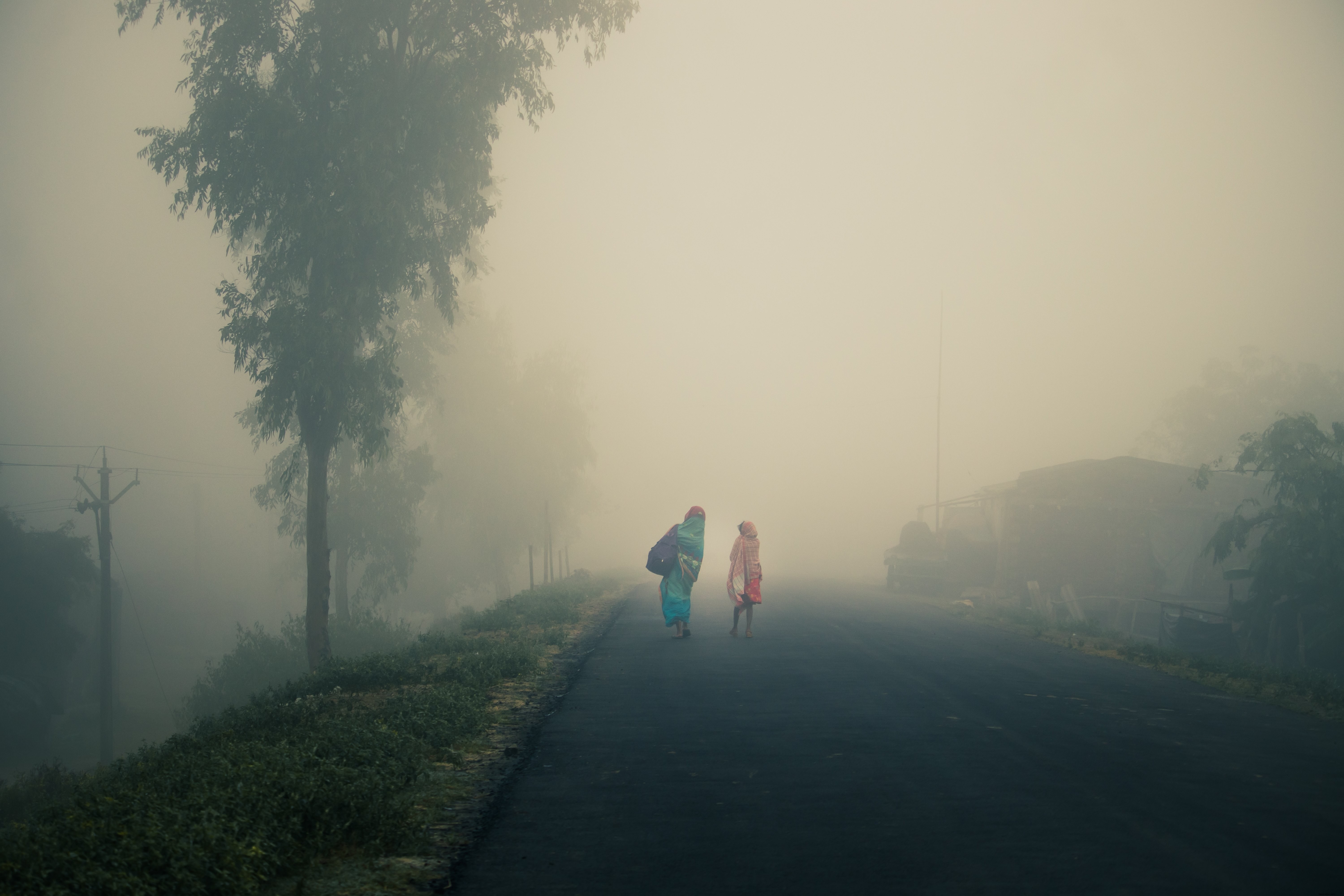 Dos personas caminan en una foto de carretera neblinosa vacía 