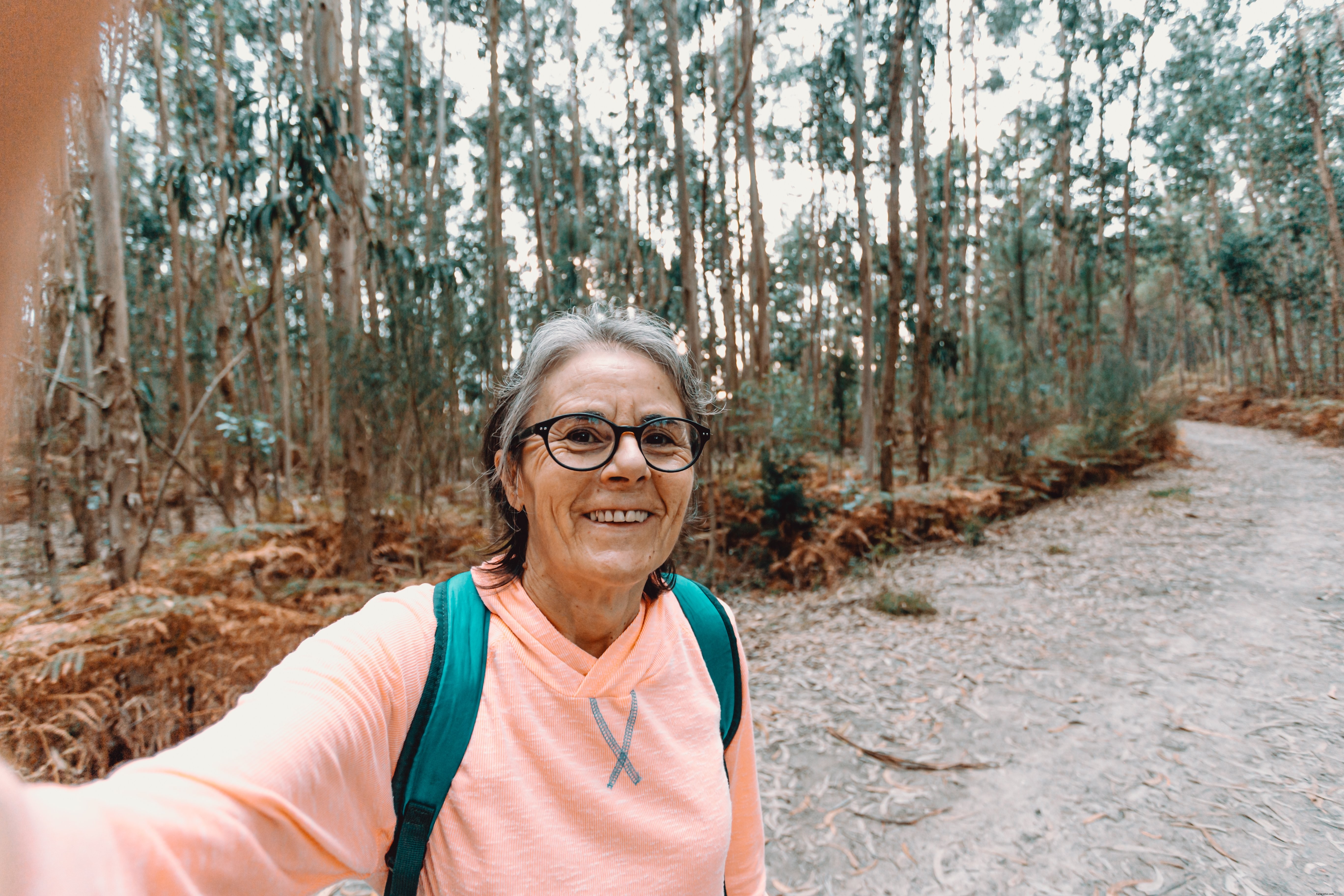 Mulher sorri e tira uma selfie durante uma caminhada. Foto 