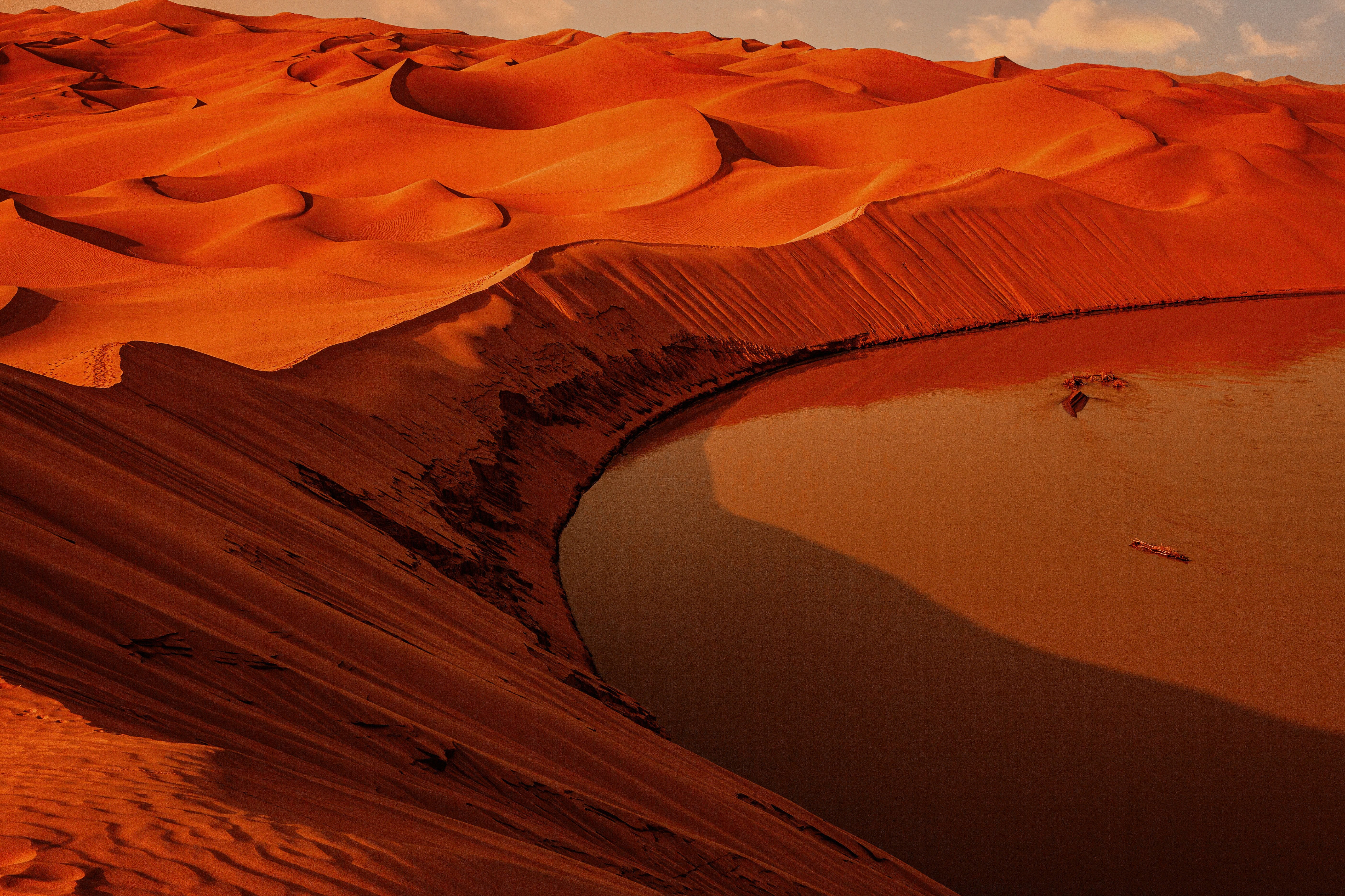 まだオレンジ色の水に会うための活気に満ちた砂丘の曲線写真 