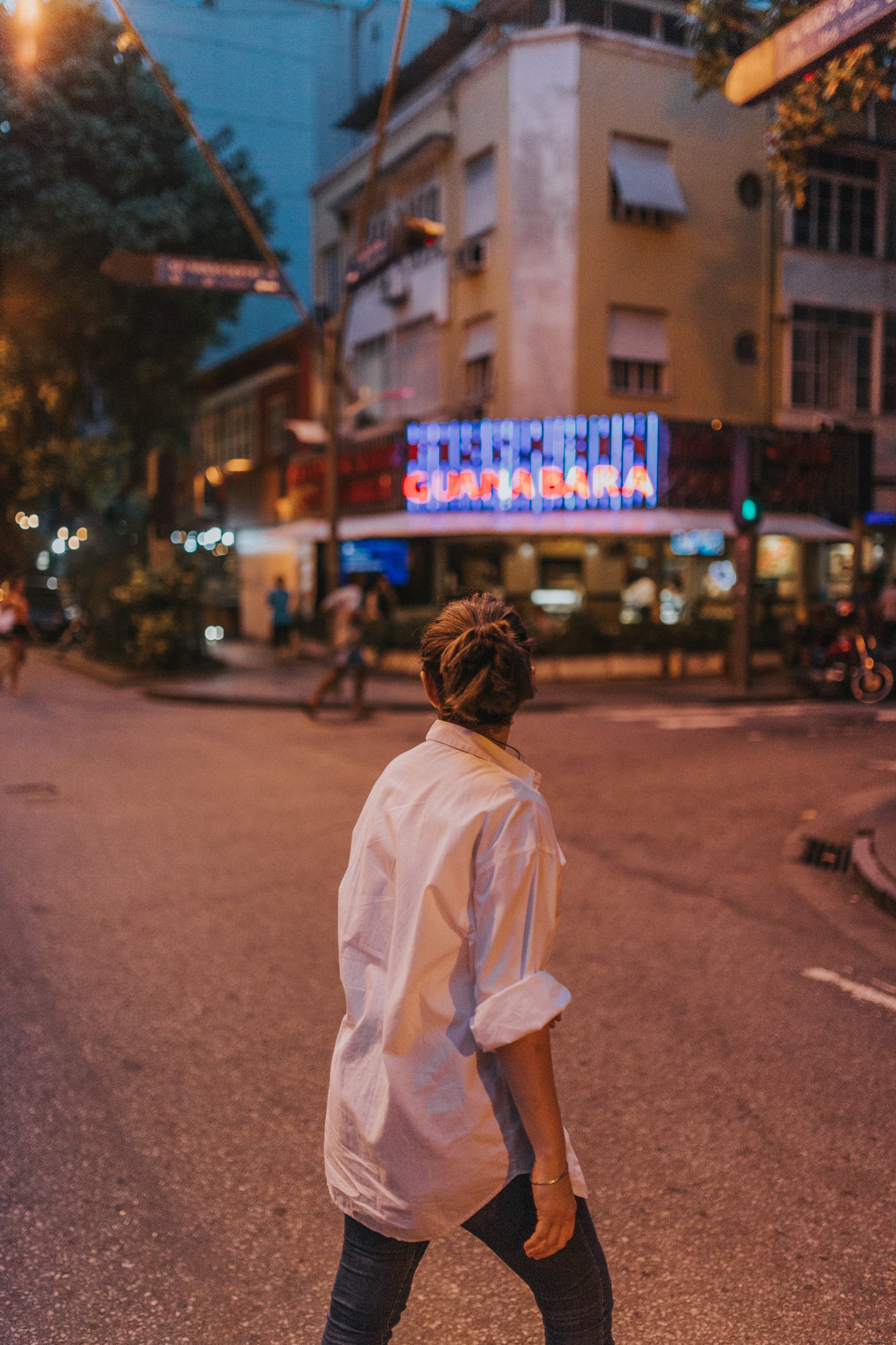 Pessoa com uma camisa branca caminha pela rua Foto 