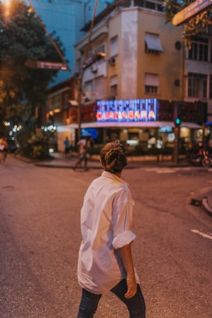 Pessoa com uma camisa branca caminha pela rua Foto 