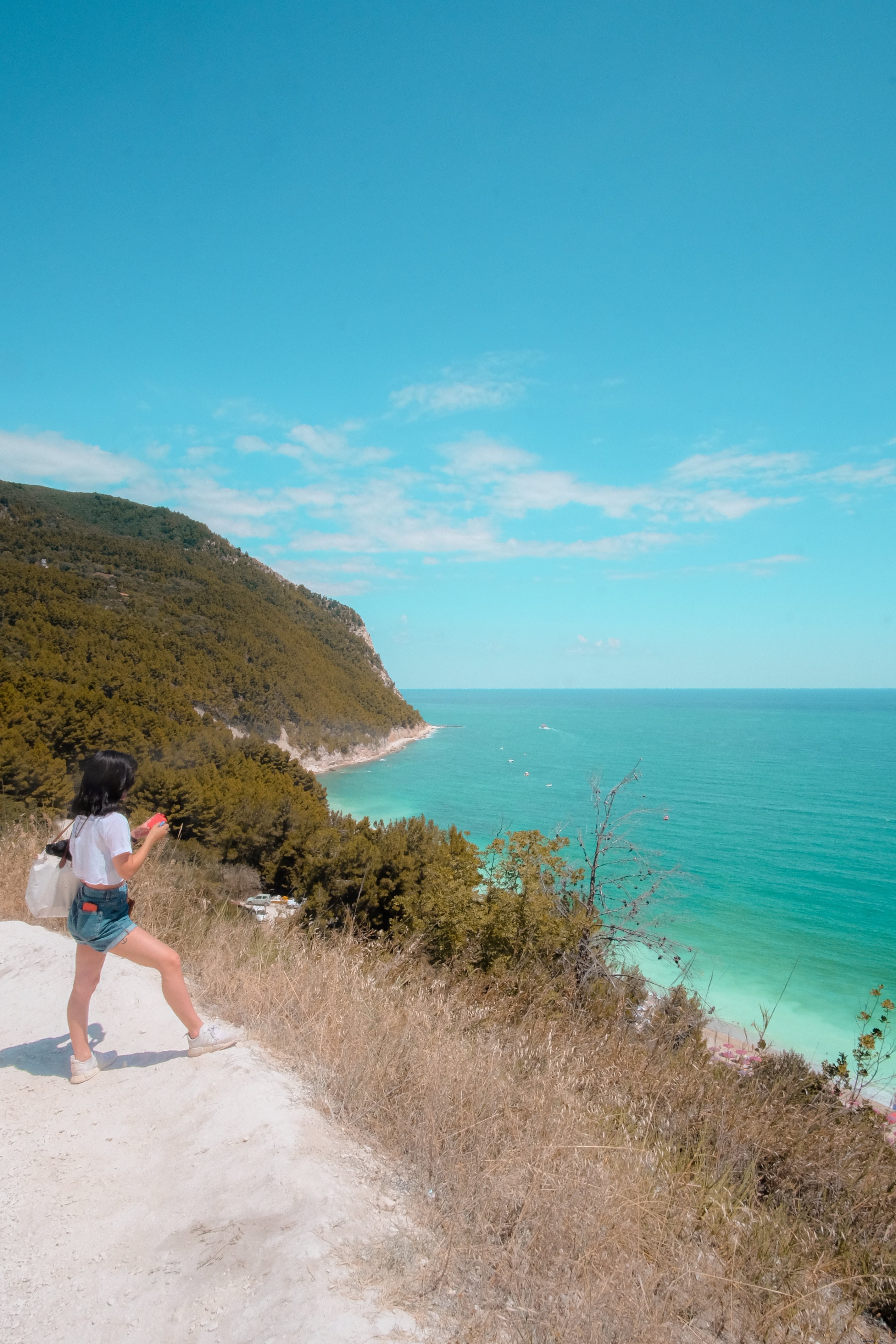 Persona in piedi su una collina di sabbia bianca che guarda verso l oceano Foto 