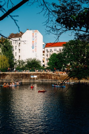 Kayaks flotan en el río con edificios detrás Foto 