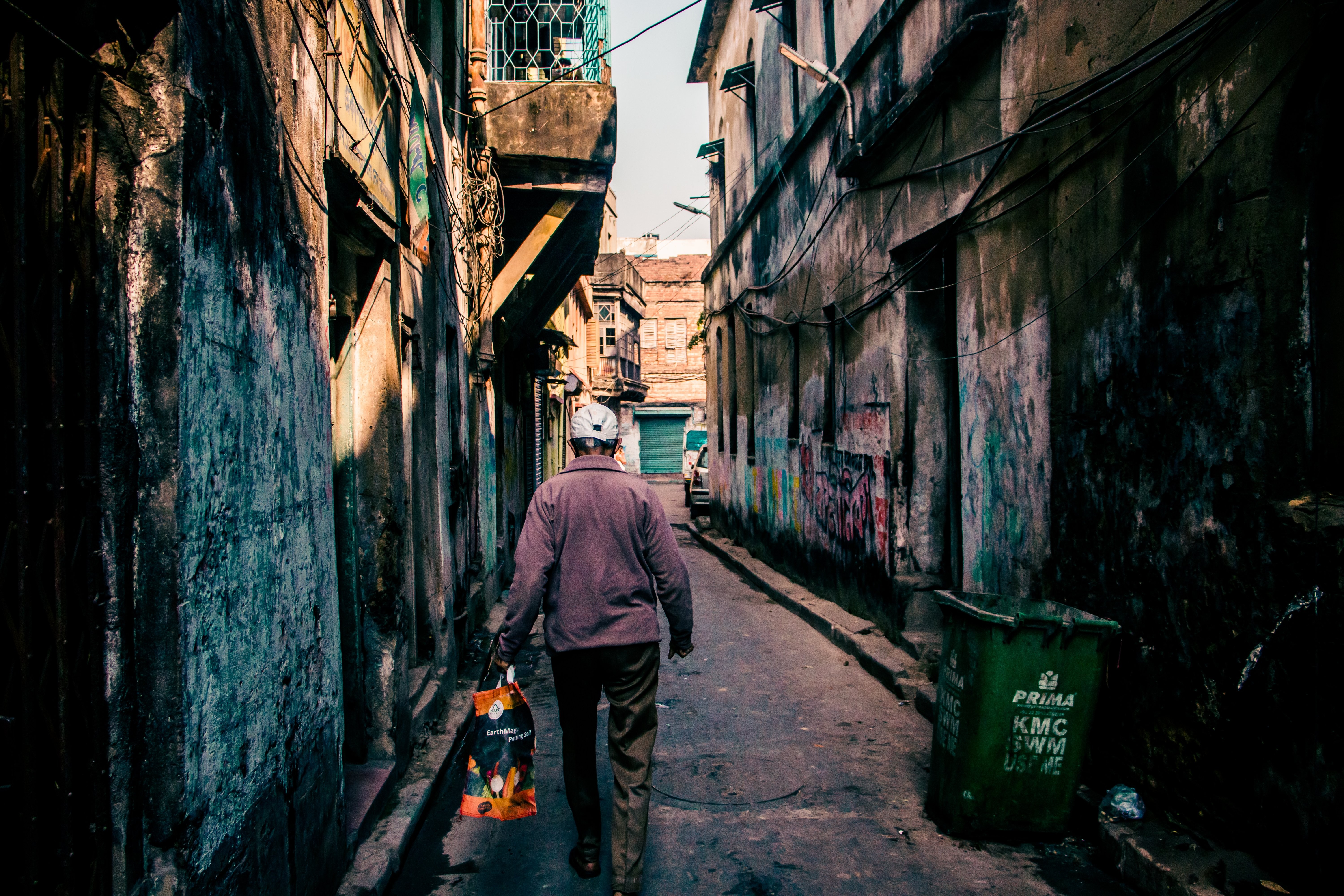 Foto de pessoa caminhando em um beco coberto de grafite 