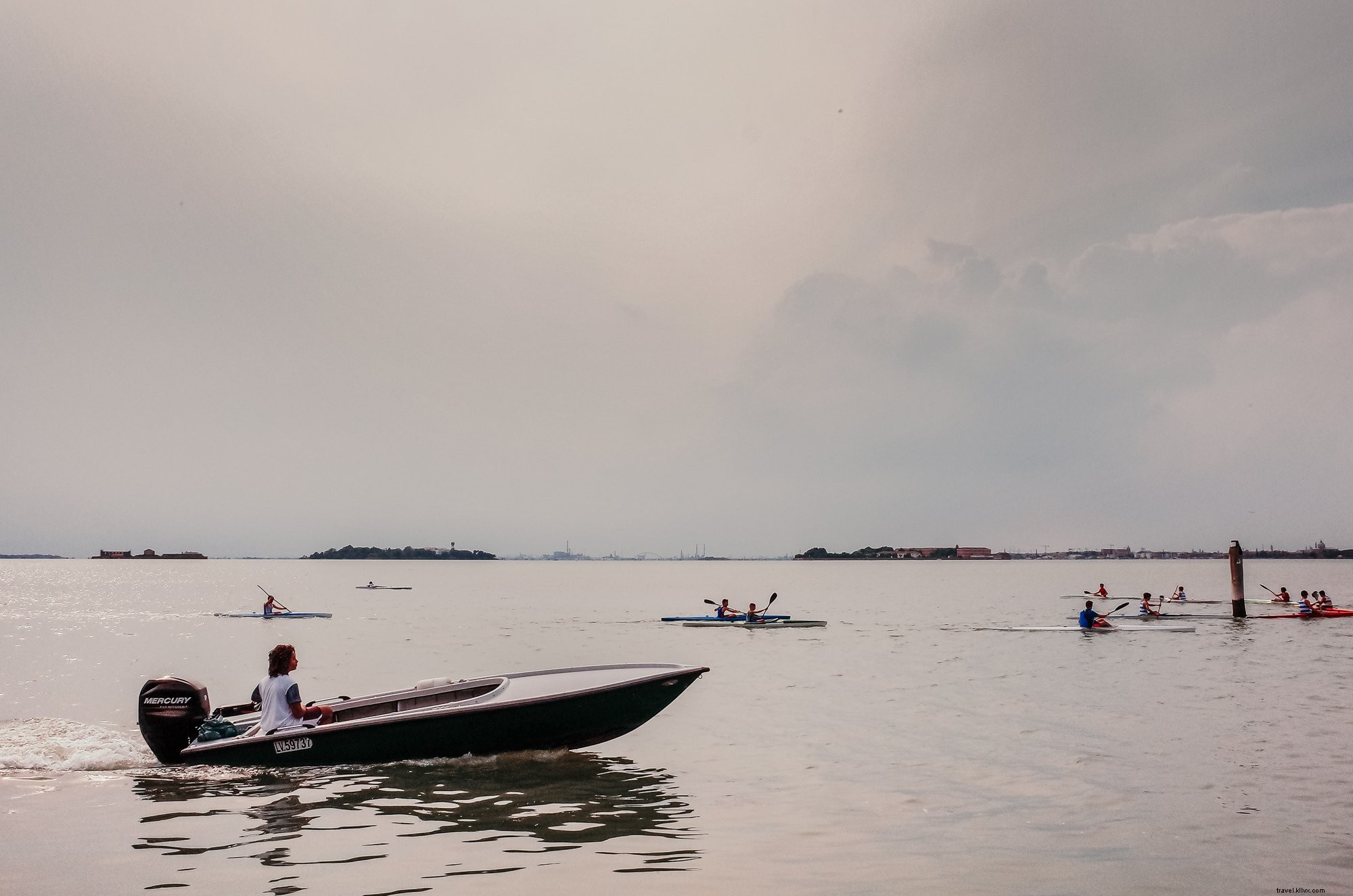 Pessoas caem de caiaque em um dia nublado com um barco seguindo a foto 