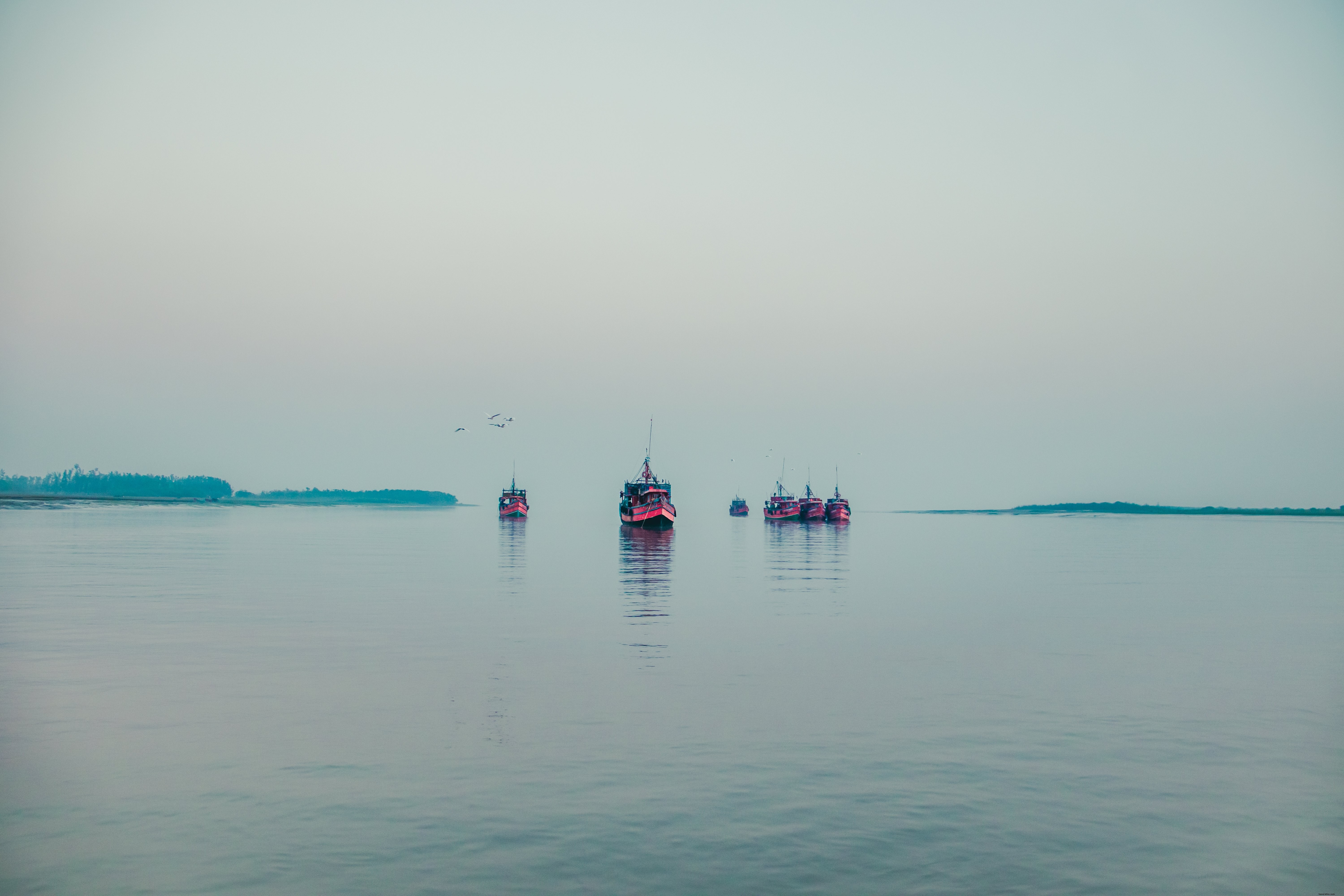 Barcos vermelhos flutuam na água em uma foto de dia nublado 