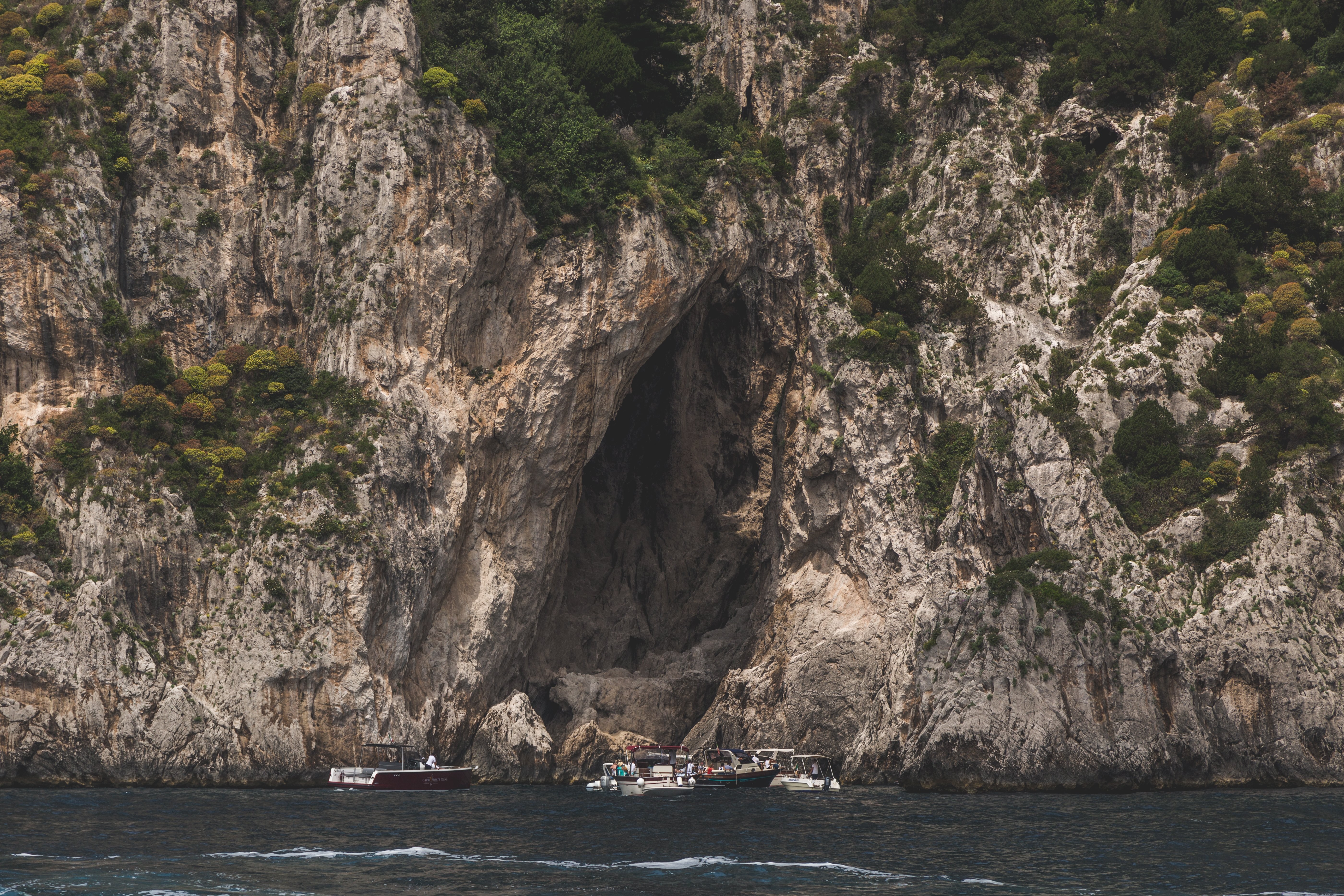 Barcos param em uma foto ao lado de um penhasco 