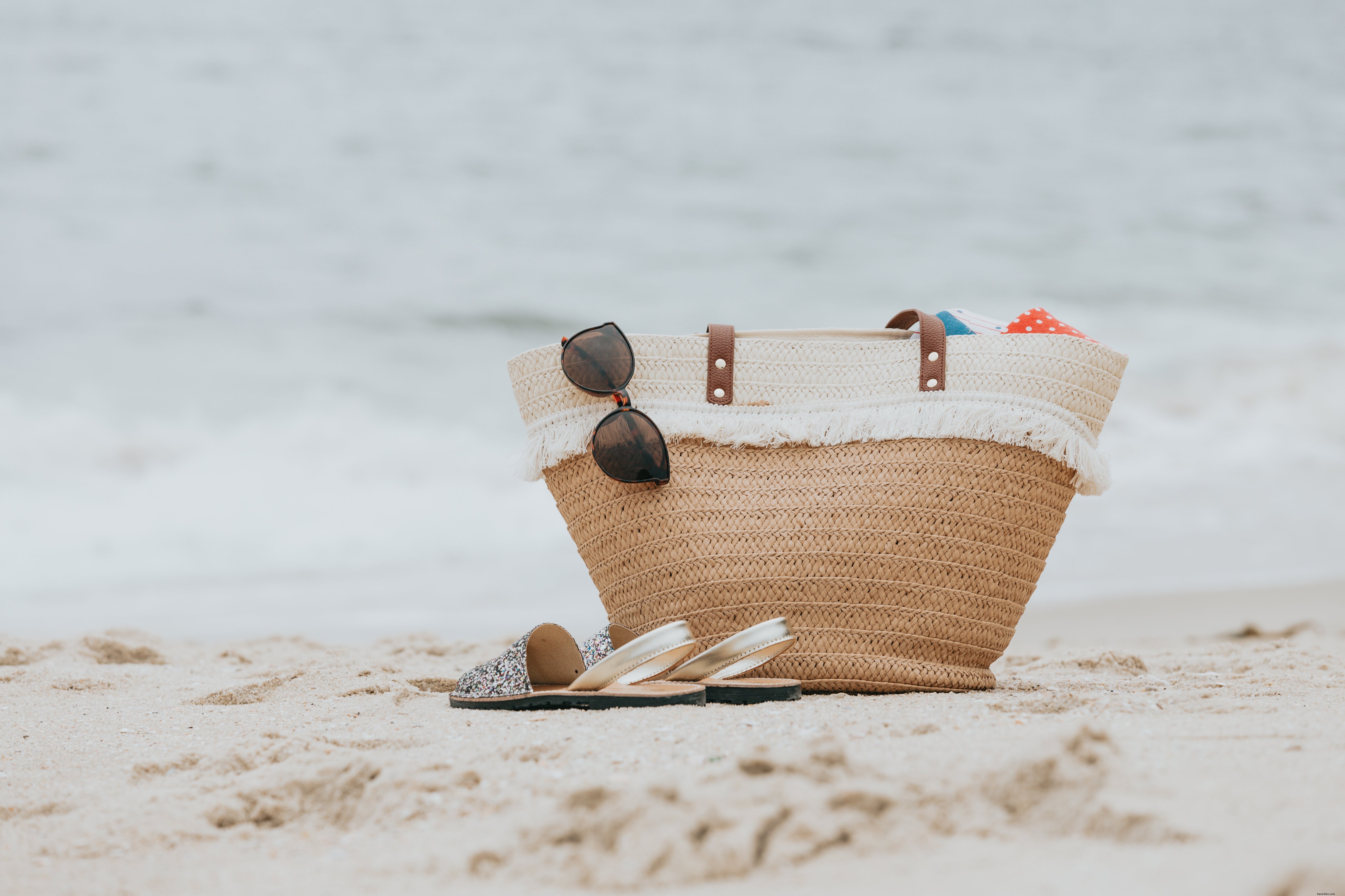 白い砂浜の写真のサンダルとビーチバッグ 