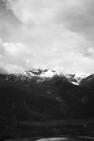 Topo de montanhas sob um céu nublado em foto monocromática 
