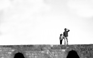 Deux personnes debout sur un pont de pierre en photo noir et blanc 