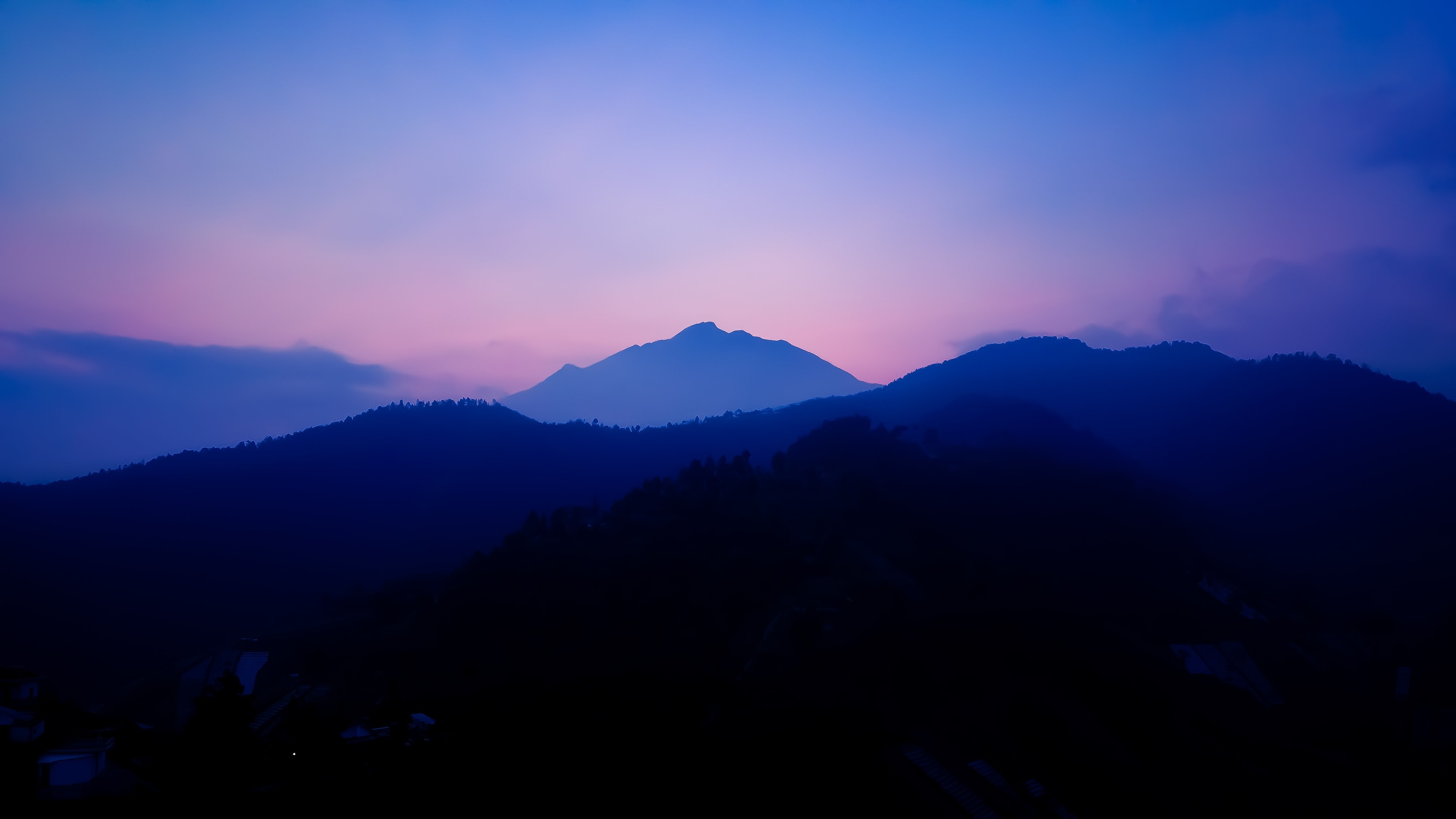 青い丘の風景と日没時のピンクの空の写真 
