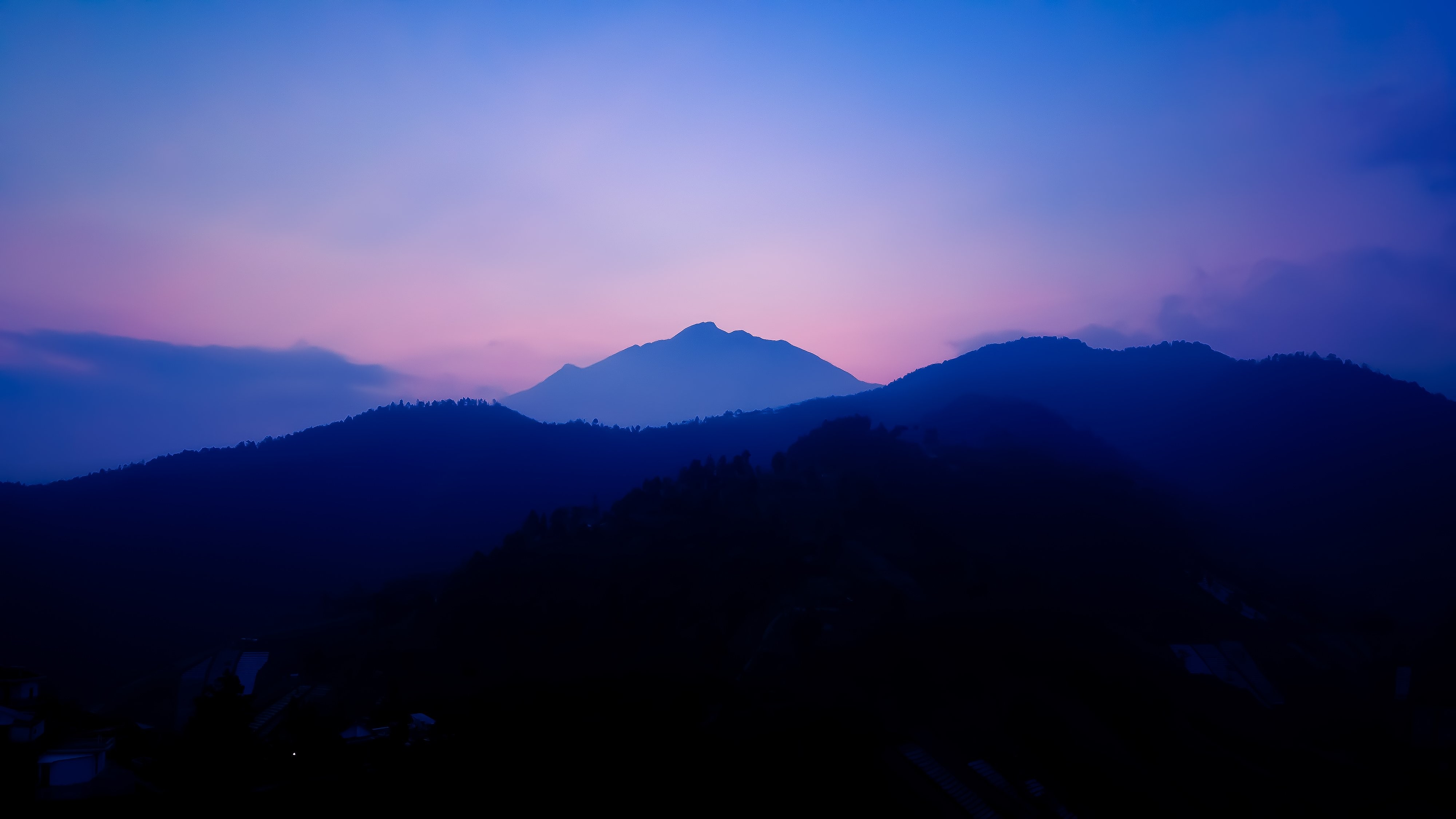 Paisaje de colinas azules y un cielo rosa al atardecer 