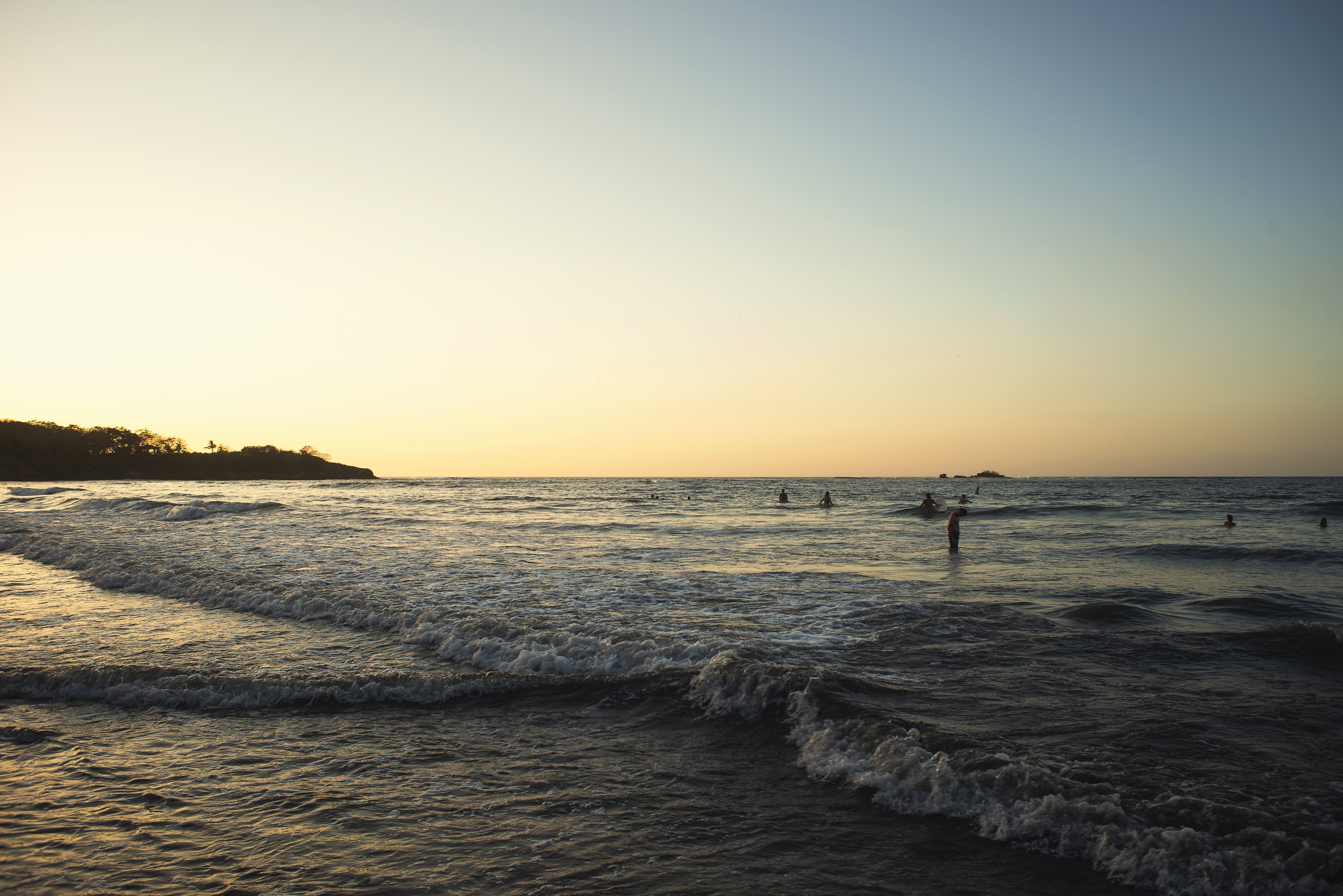 Foto de puesta de sol sobre surfistas y amantes de la playa 