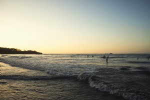 Foto do sol se pondo sobre surfistas e banhistas 