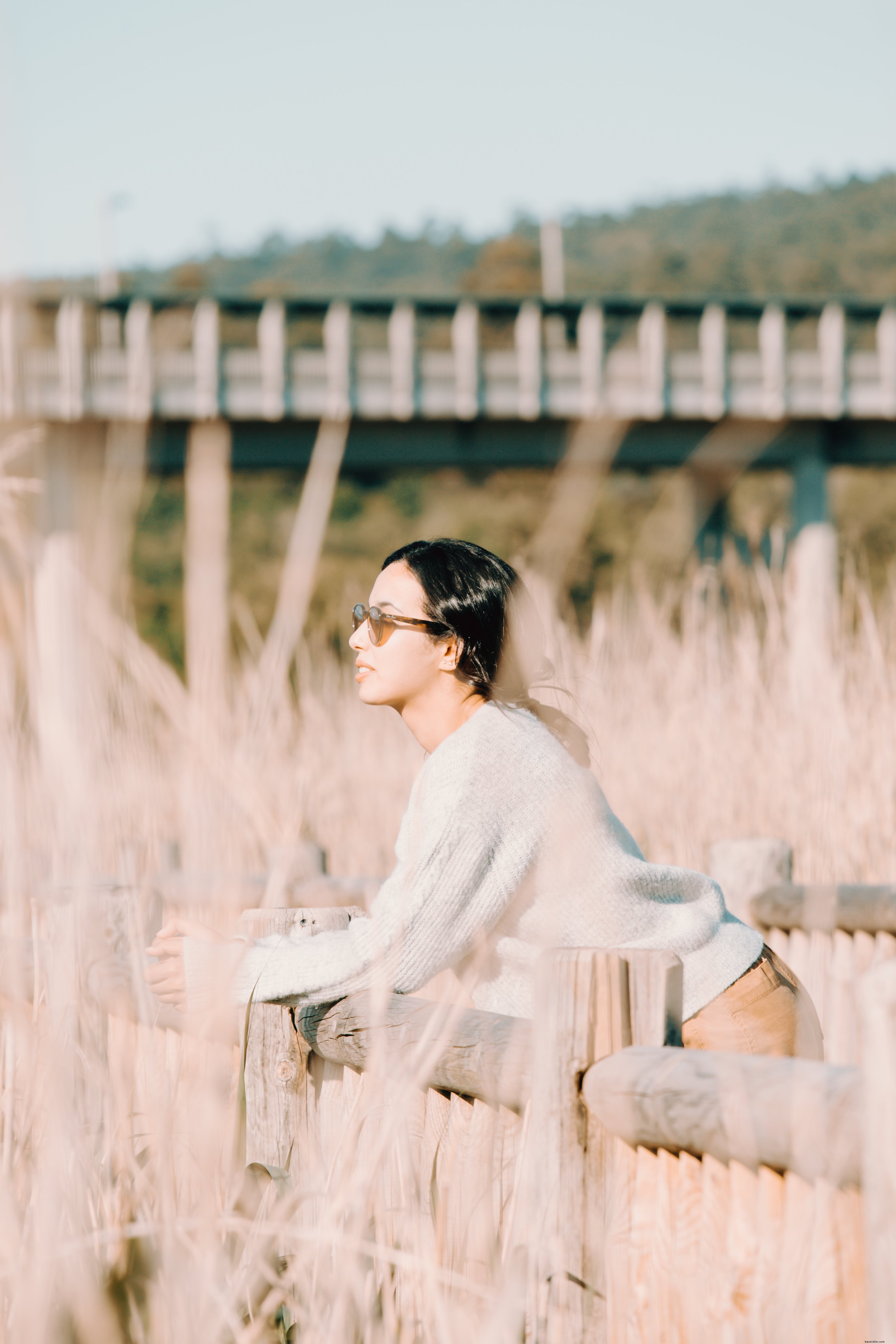 女性は屋外の木製の柵で休む写真 