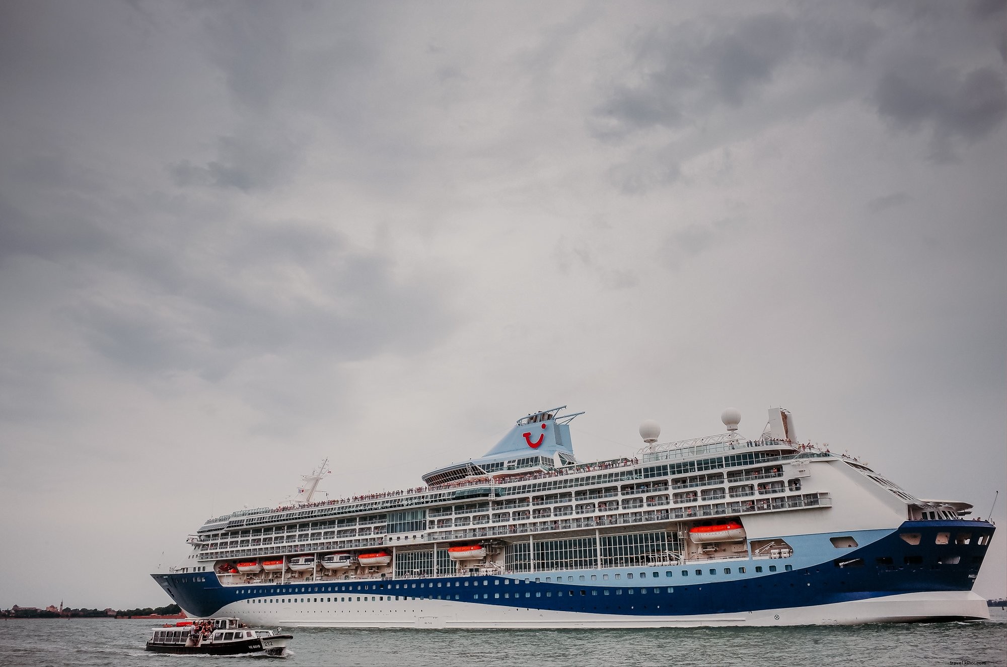 Foto de grande navio de cruzeiro branco e azul em um dia nublado 