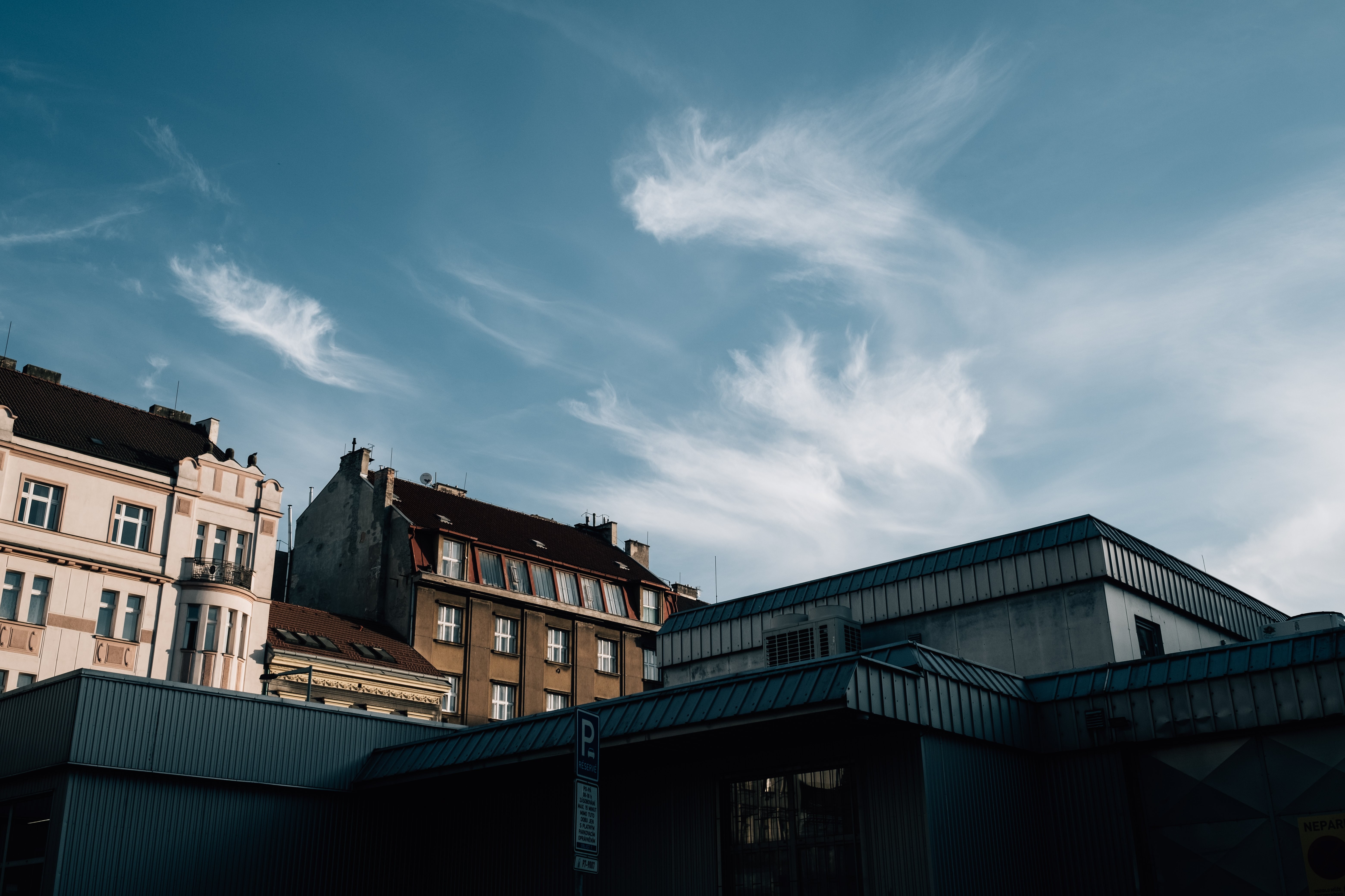 Foto do céu azul com nuvens finas sobre telhados de edifícios 