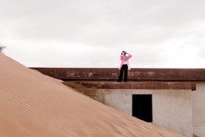 Personne dans une veste rose se dresse sur le bâtiment couvert de sable Photo 