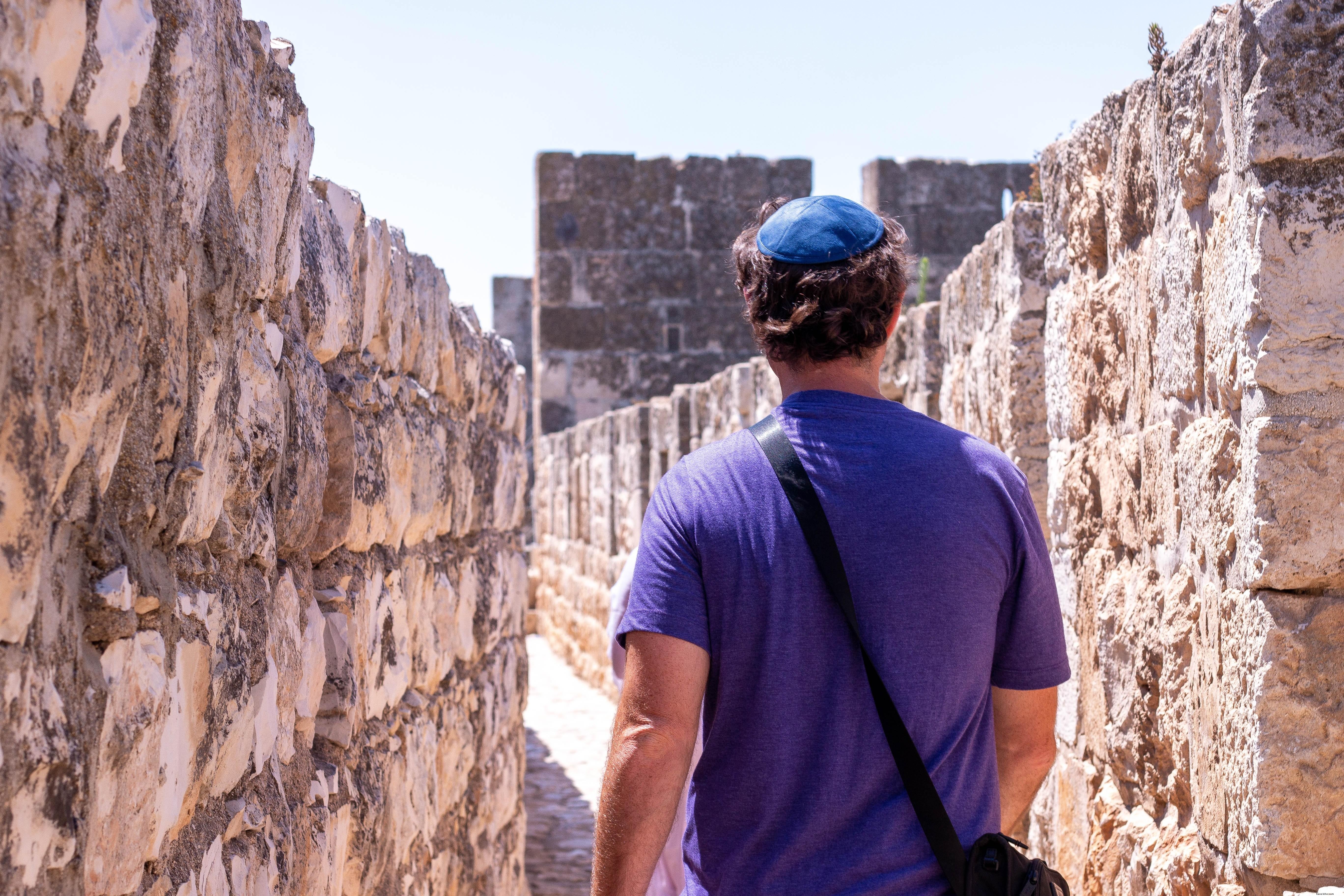 Foto de uma pessoa de púrpura caminhando entre duas paredes de pedra 