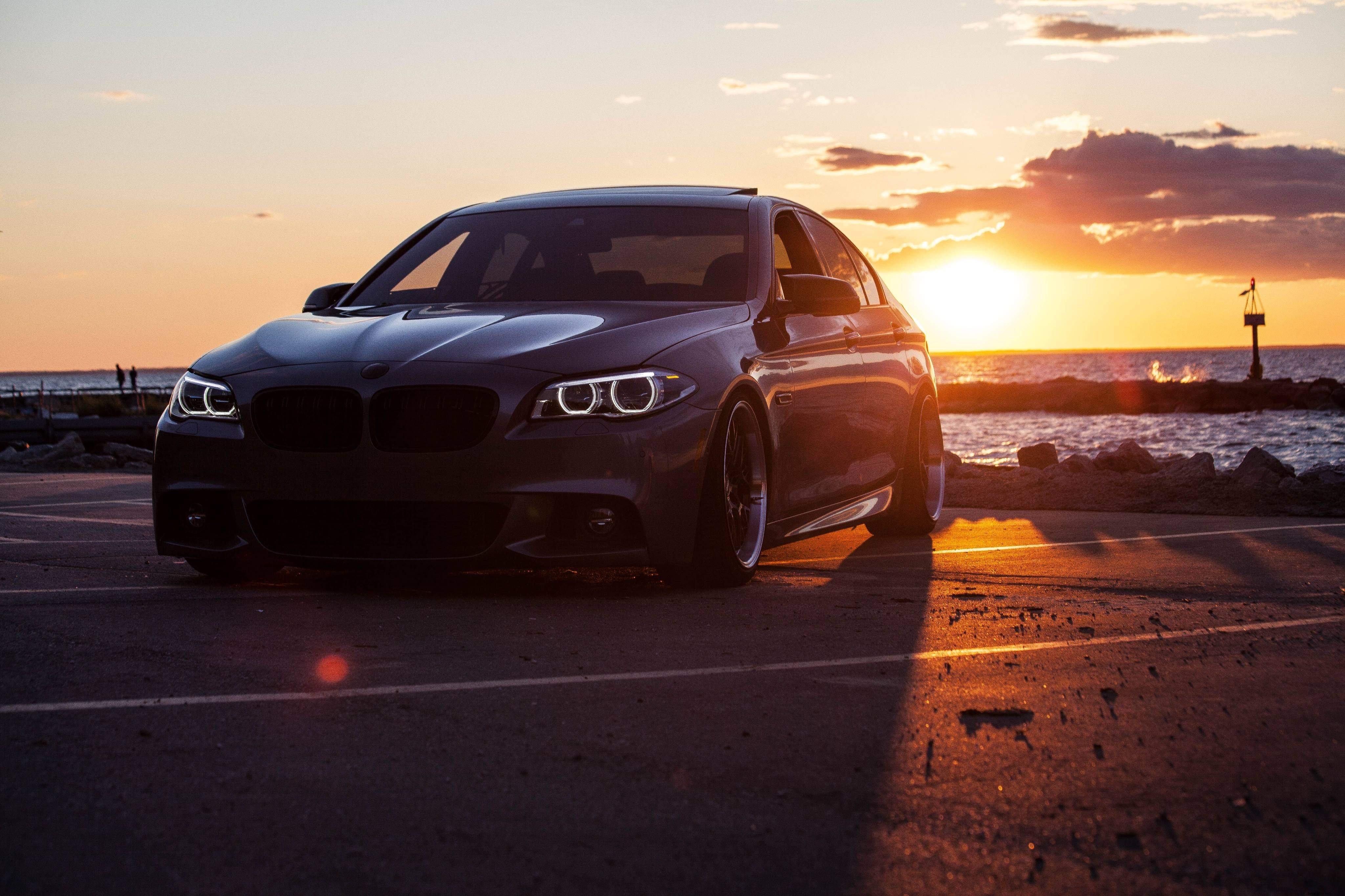 Carro estacionado perto da água ao pôr do sol Foto 