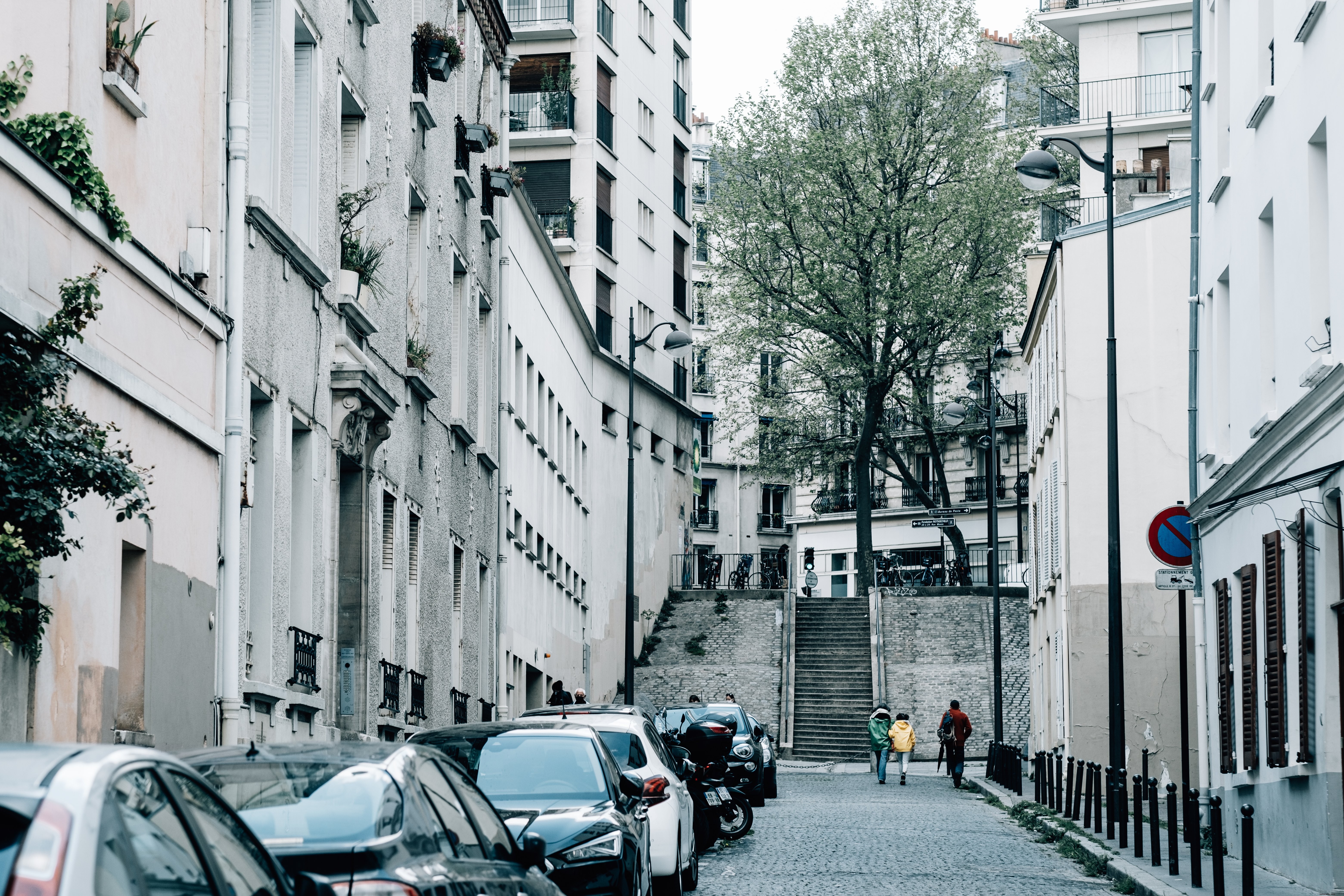 Rua da cidade com fotos de carros e três pedestres 