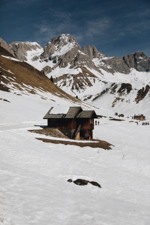 Foto de cabaña de madera debajo de montañas nevadas 