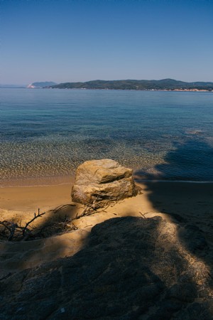Foto de rocha situada na costa do mar de areia 