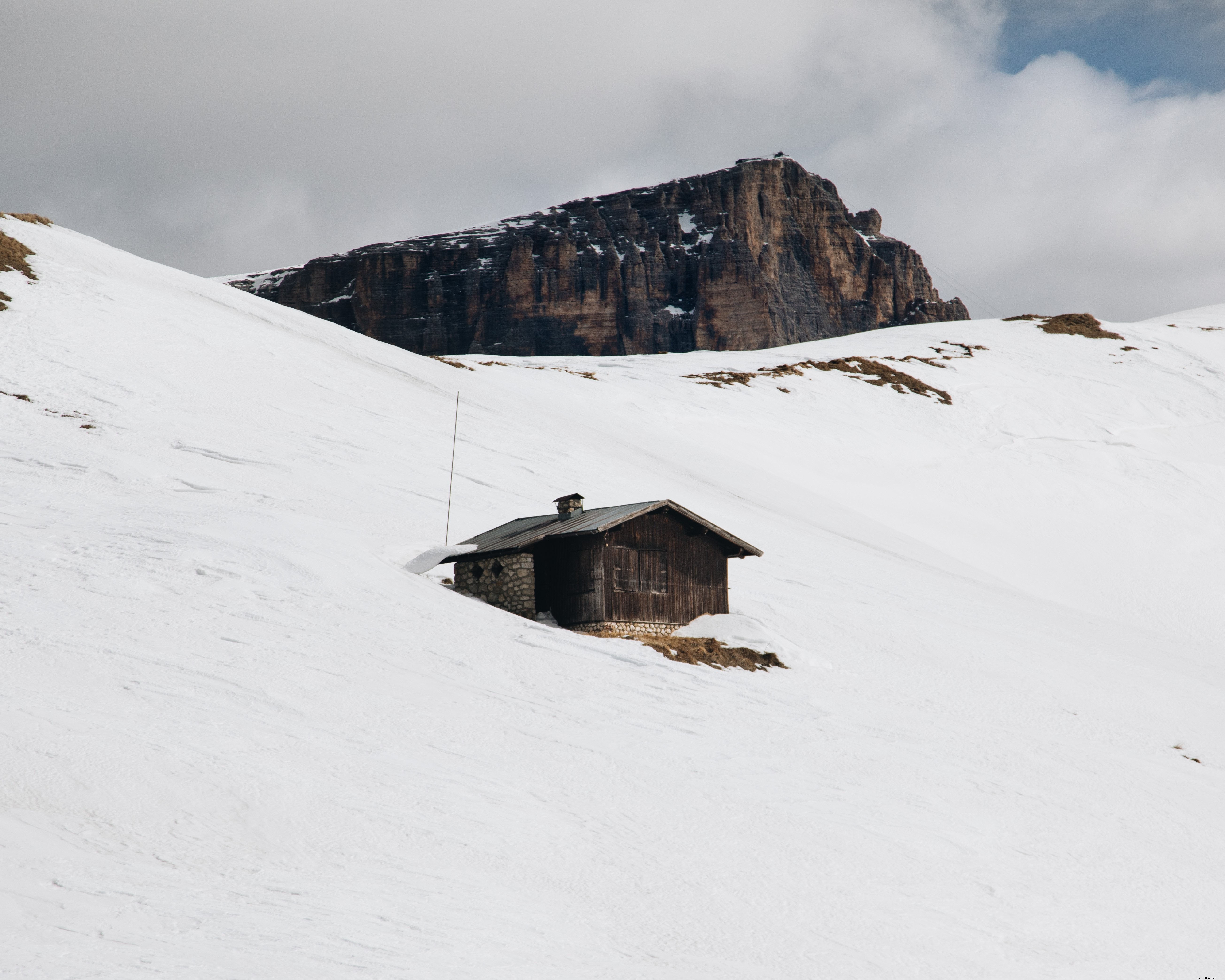 Foto de cabaña pequeña rodeada de montañas 