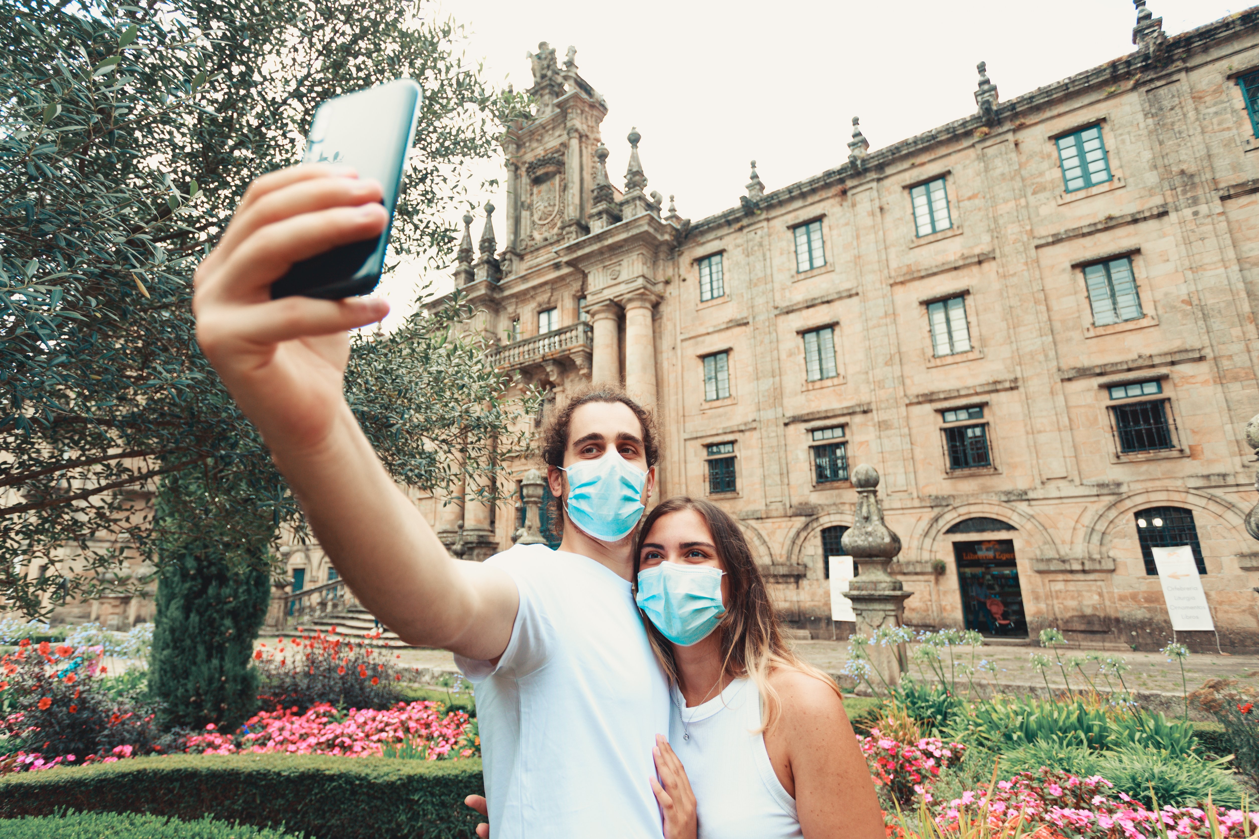 Dos personas se toman una selfie al aire libre mientras usan máscaras azules Foto 