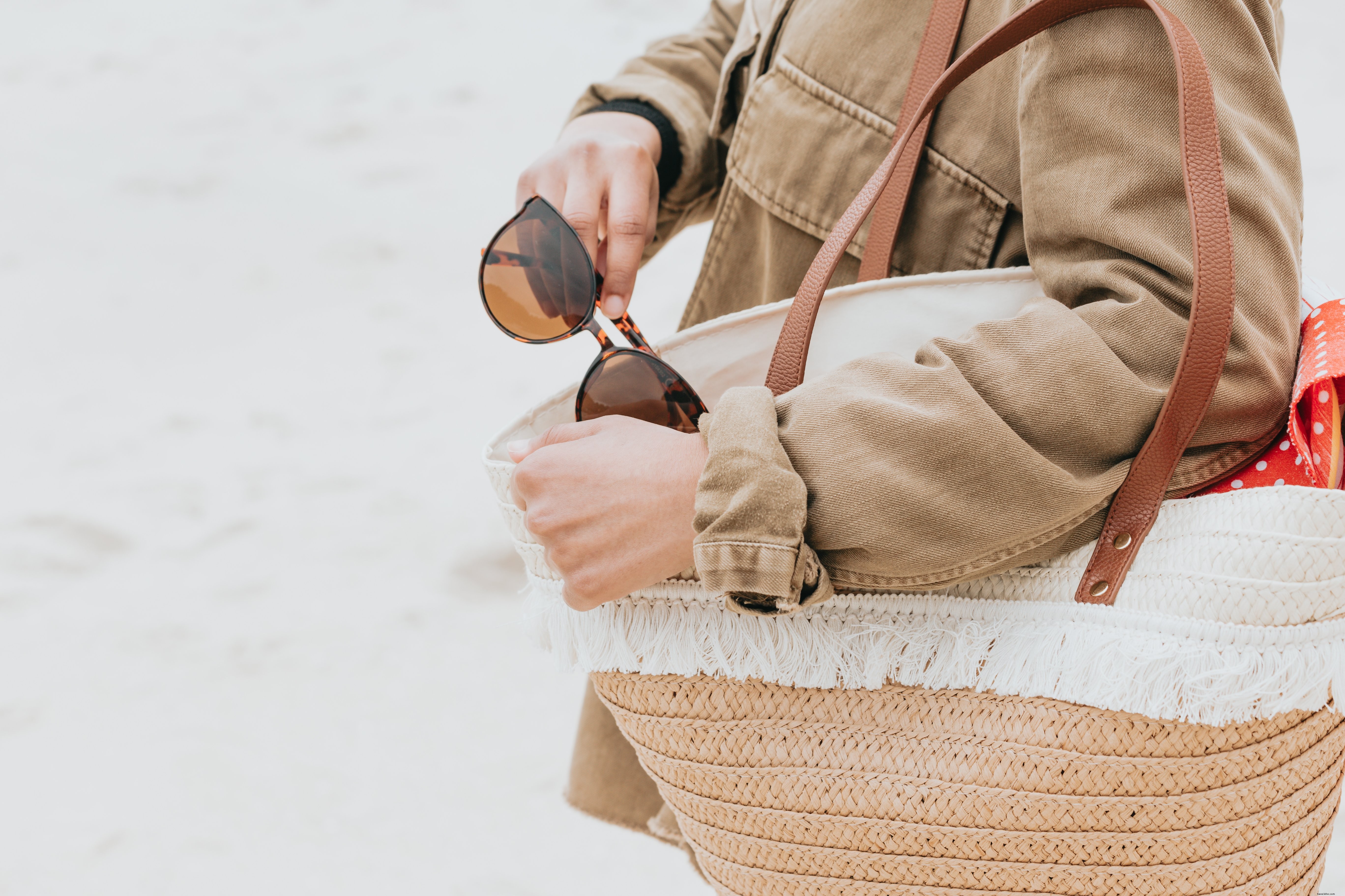 Sosteniendo una bolsa de playa y saca sus gafas de sol foto 