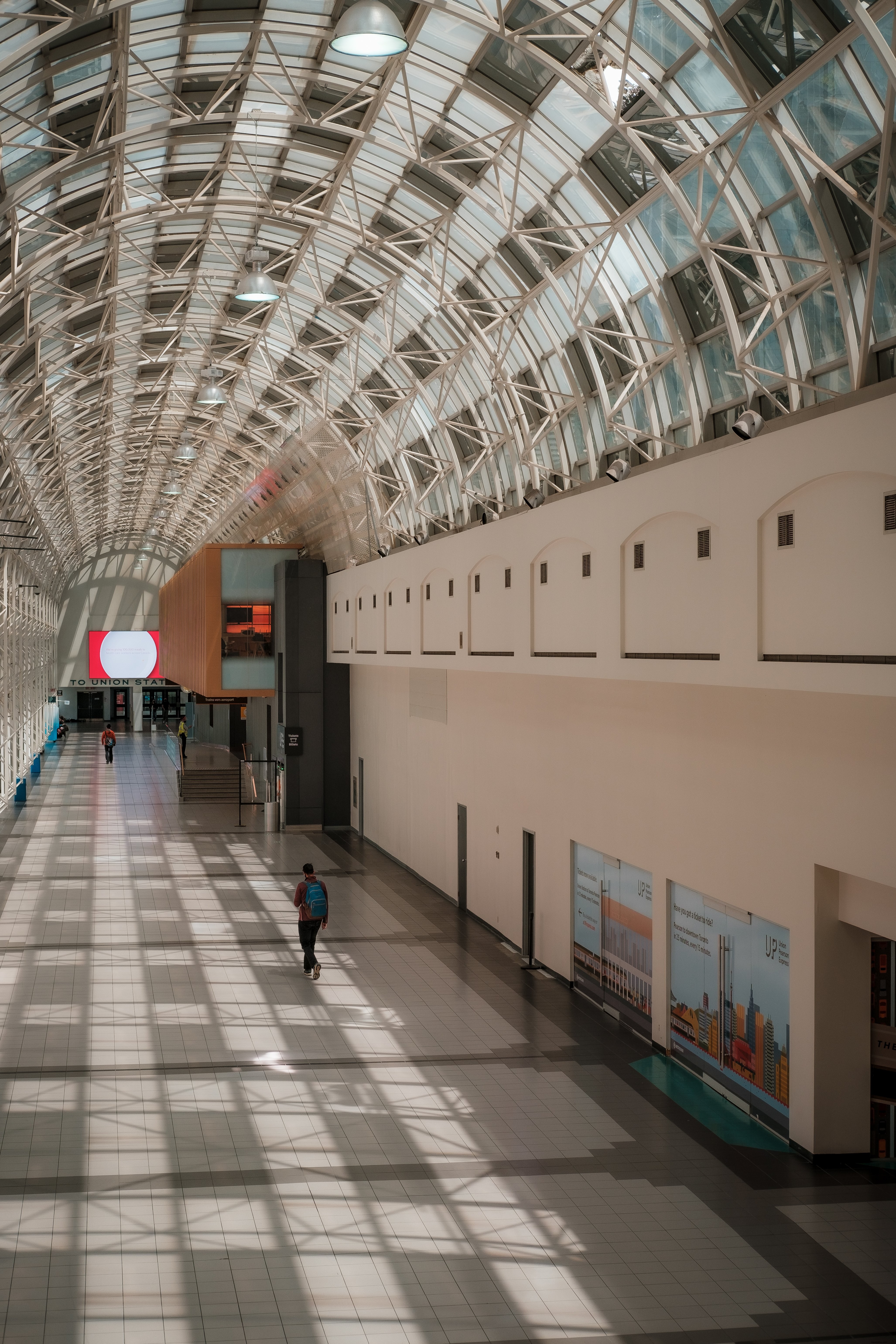 Une personne descend un large atrium avec une photo de plafond incurvé 