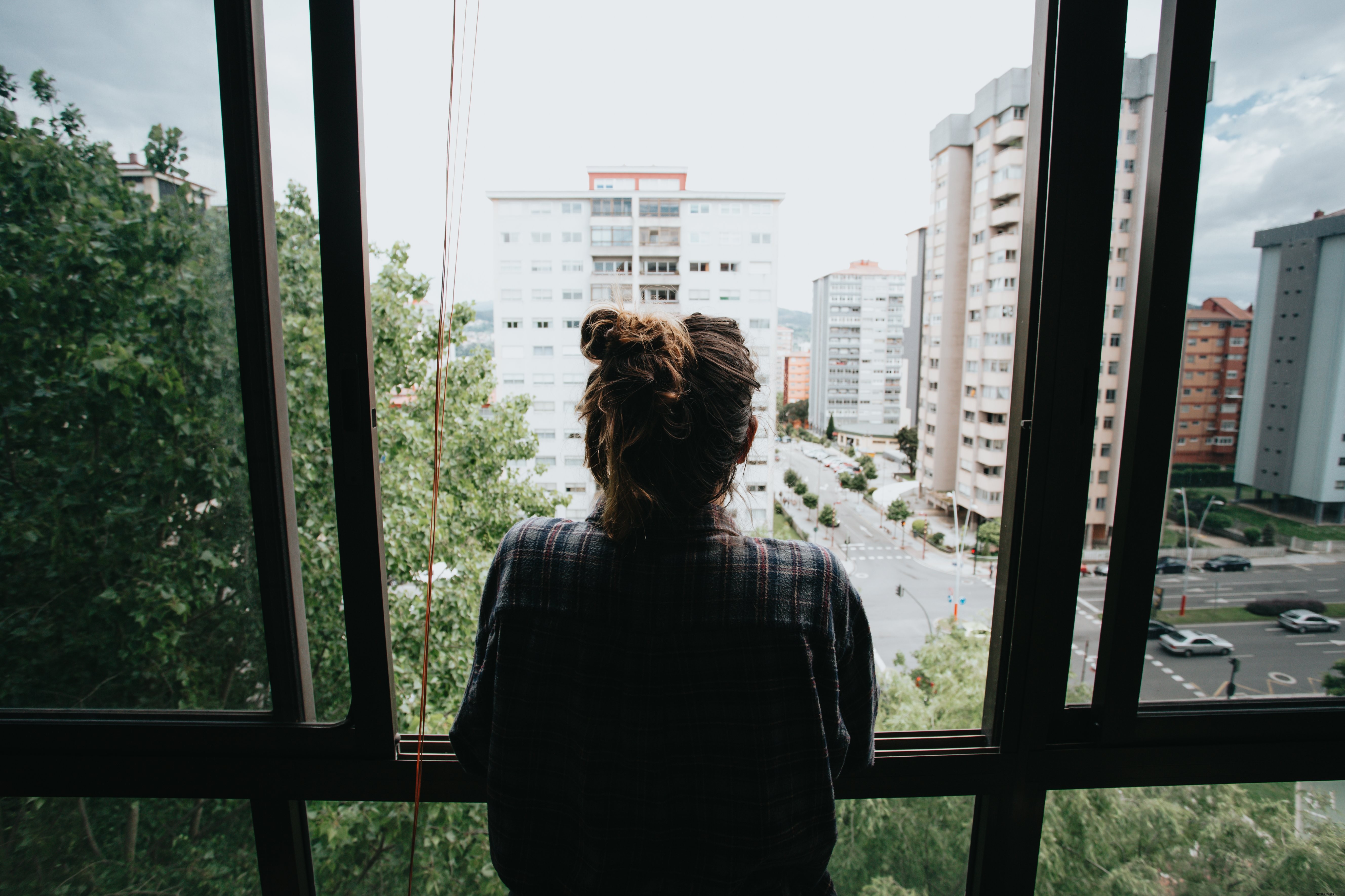 Personne regarde par une fenêtre ouverte vers la ville ci-dessous Photo 