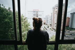 La persona guarda fuori da una finestra aperta verso la città sotto la foto 