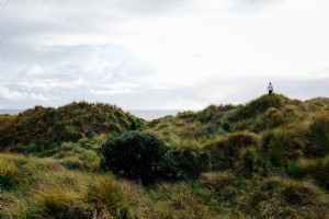 Foto de mujer se aleja a través de las dunas cubiertas de hierba 