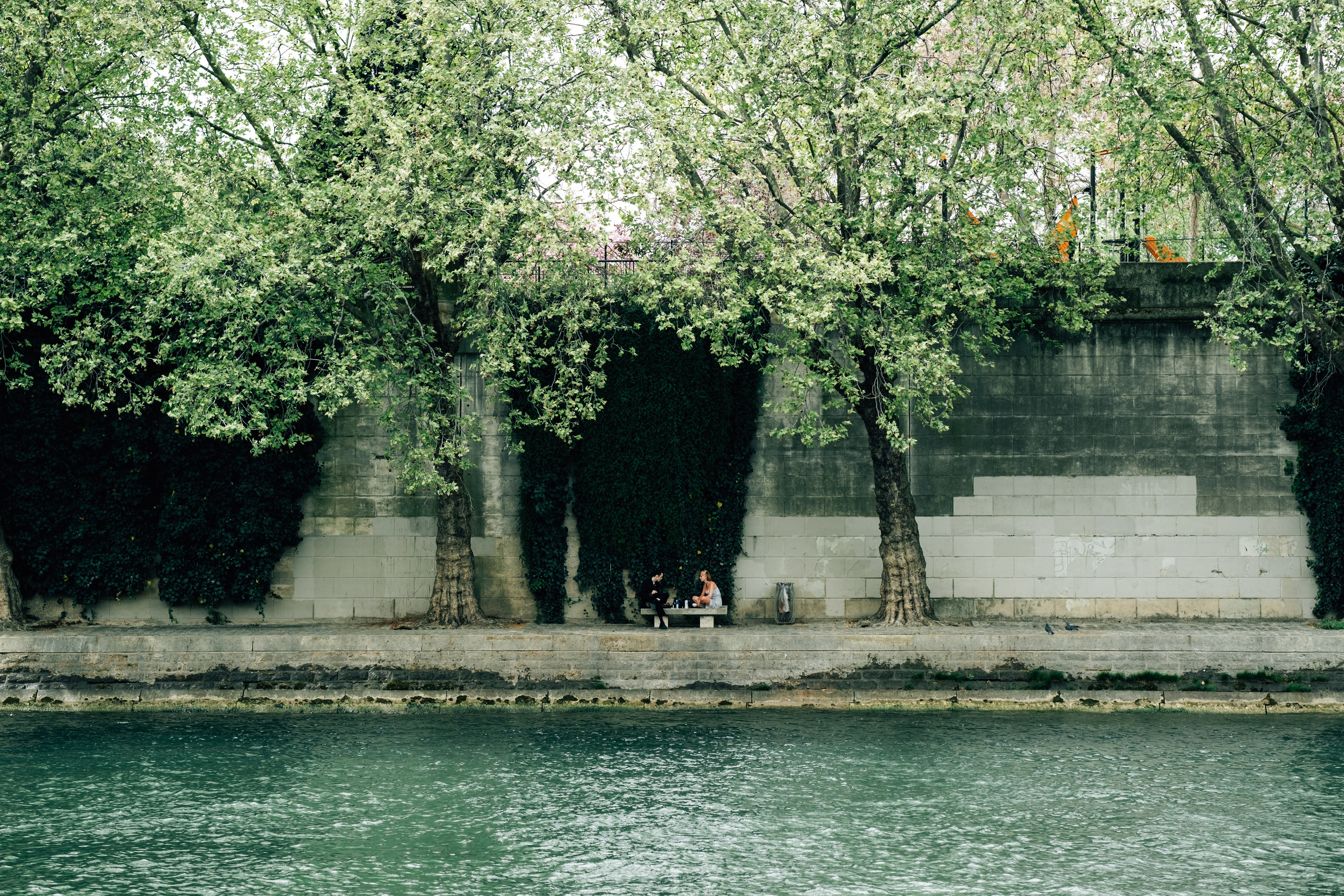 Río con gente sentada al otro lado en un banco Foto 