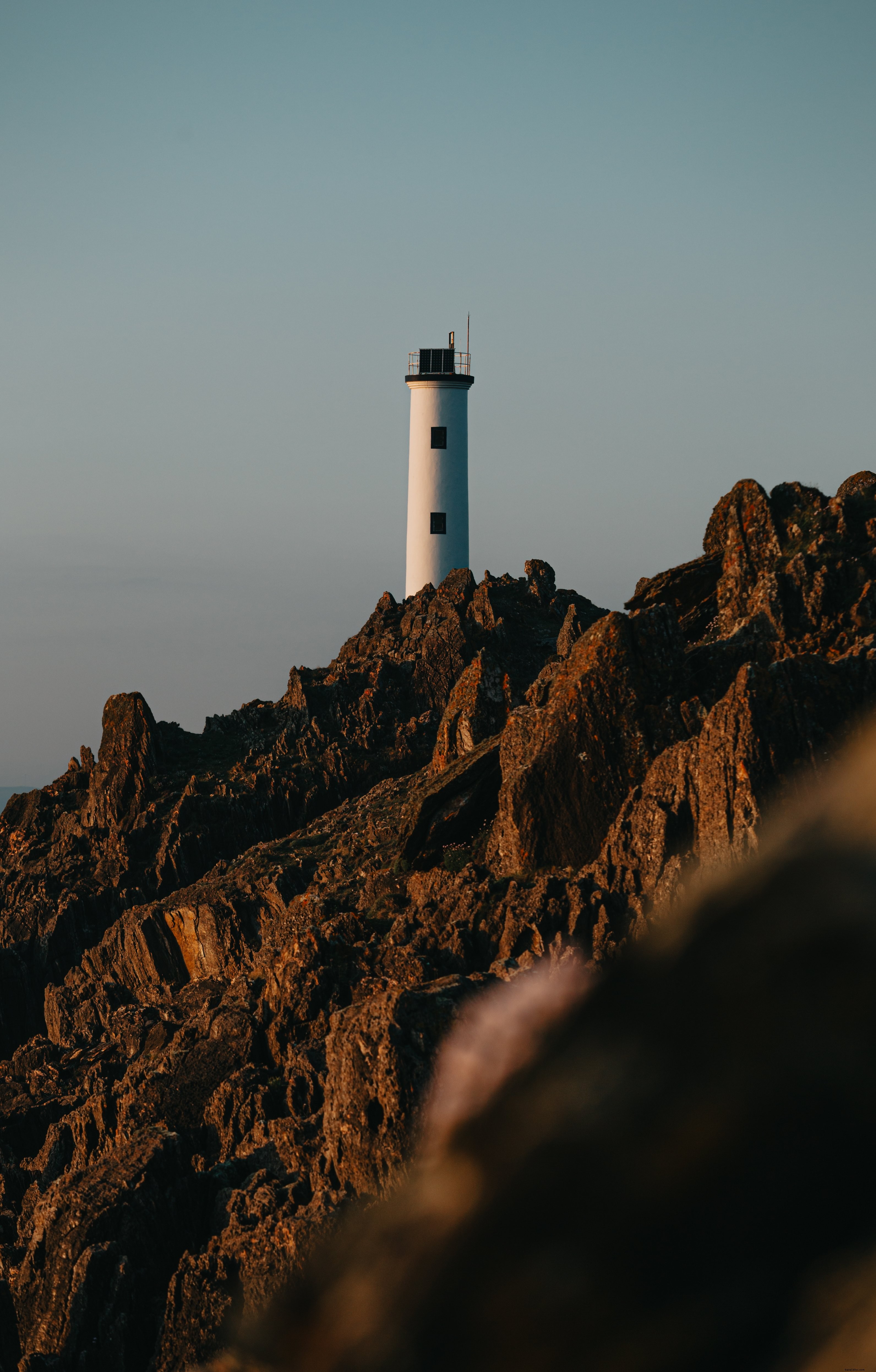 Un faro si trova in cima a una cresta affilata di una montagna Foto 