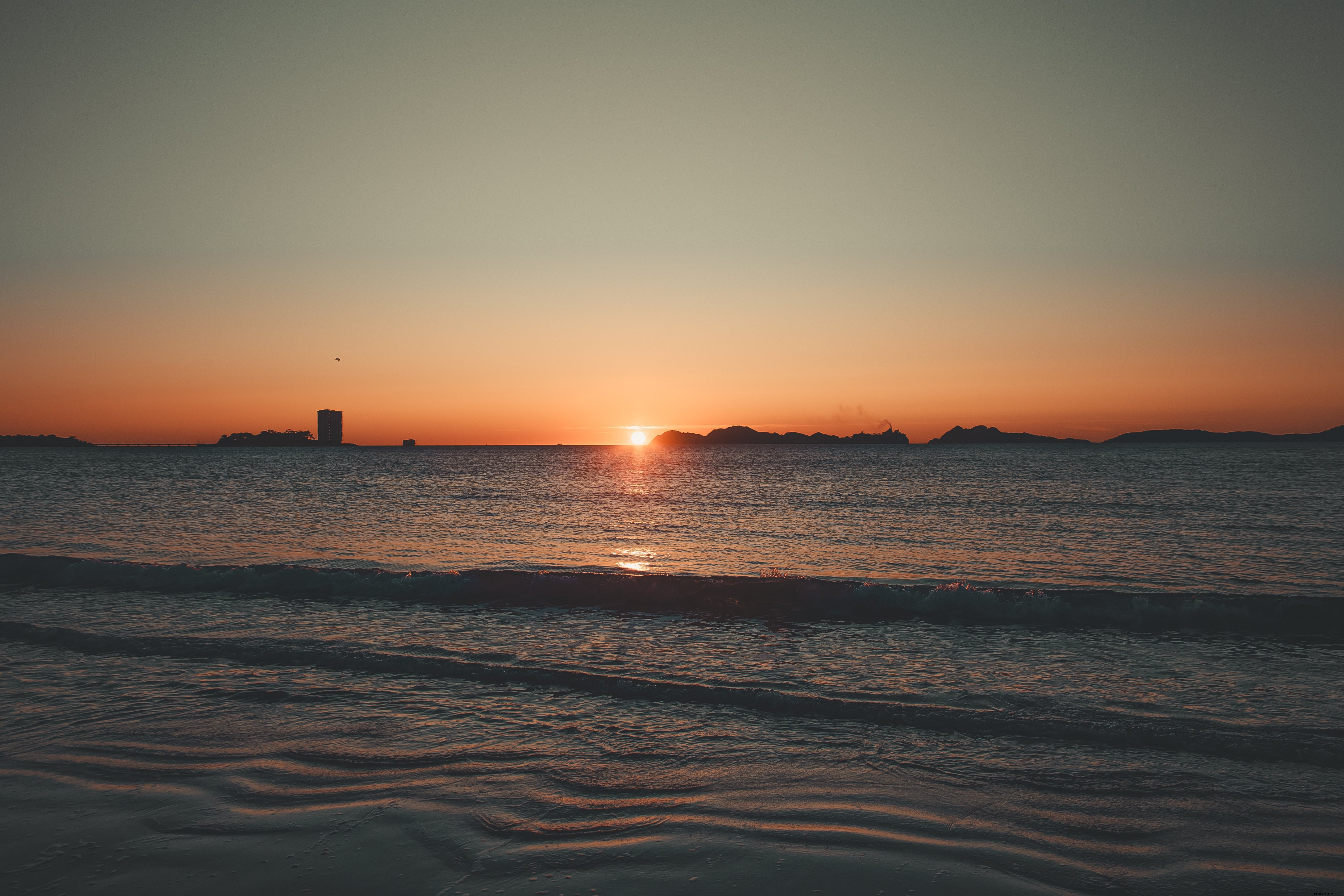 Pasang Bergulir Ke Pantai Di Bawah Matahari Terbenam Foto 