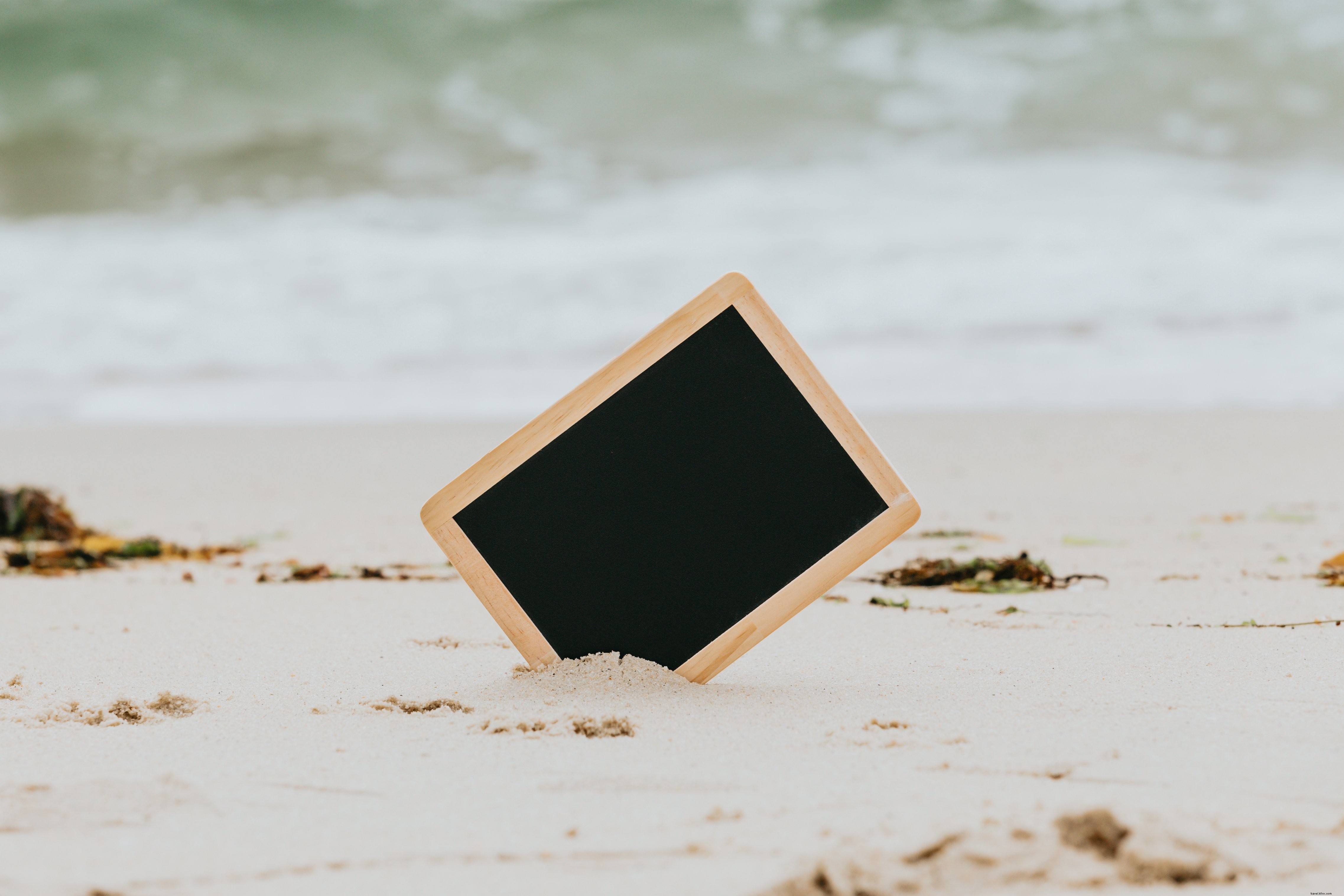 白い砂浜の写真から突き出ている黒い黒板 