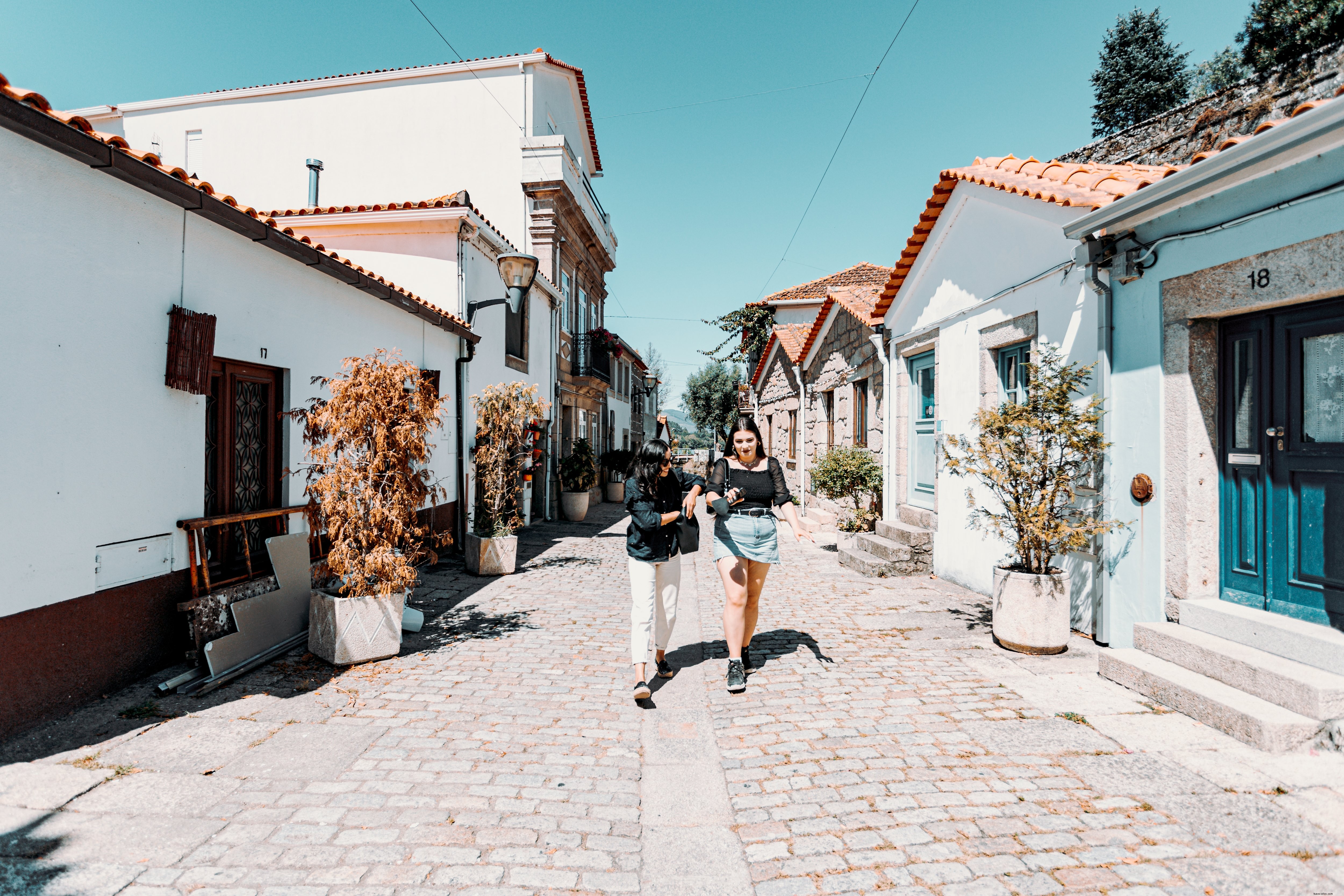 Duas mulheres caminham por um caminho com edifícios de cada lado. Foto 