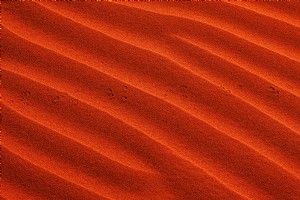 Ondas na vibrante areia alaranjada com pequenas pegadas fotográficas 