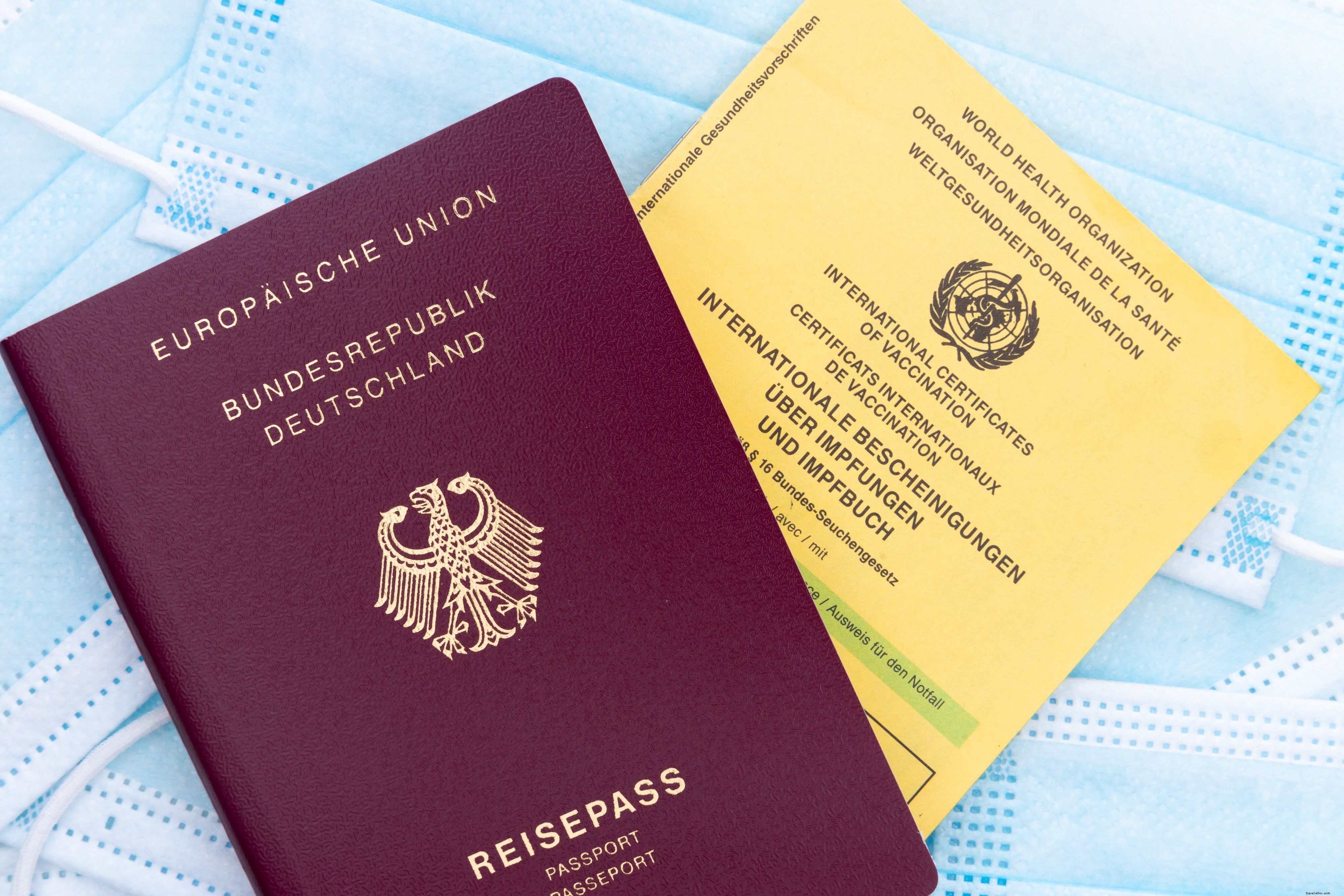 パスポートワクチンカードとフェイスマスクの写真のフラットレイ 