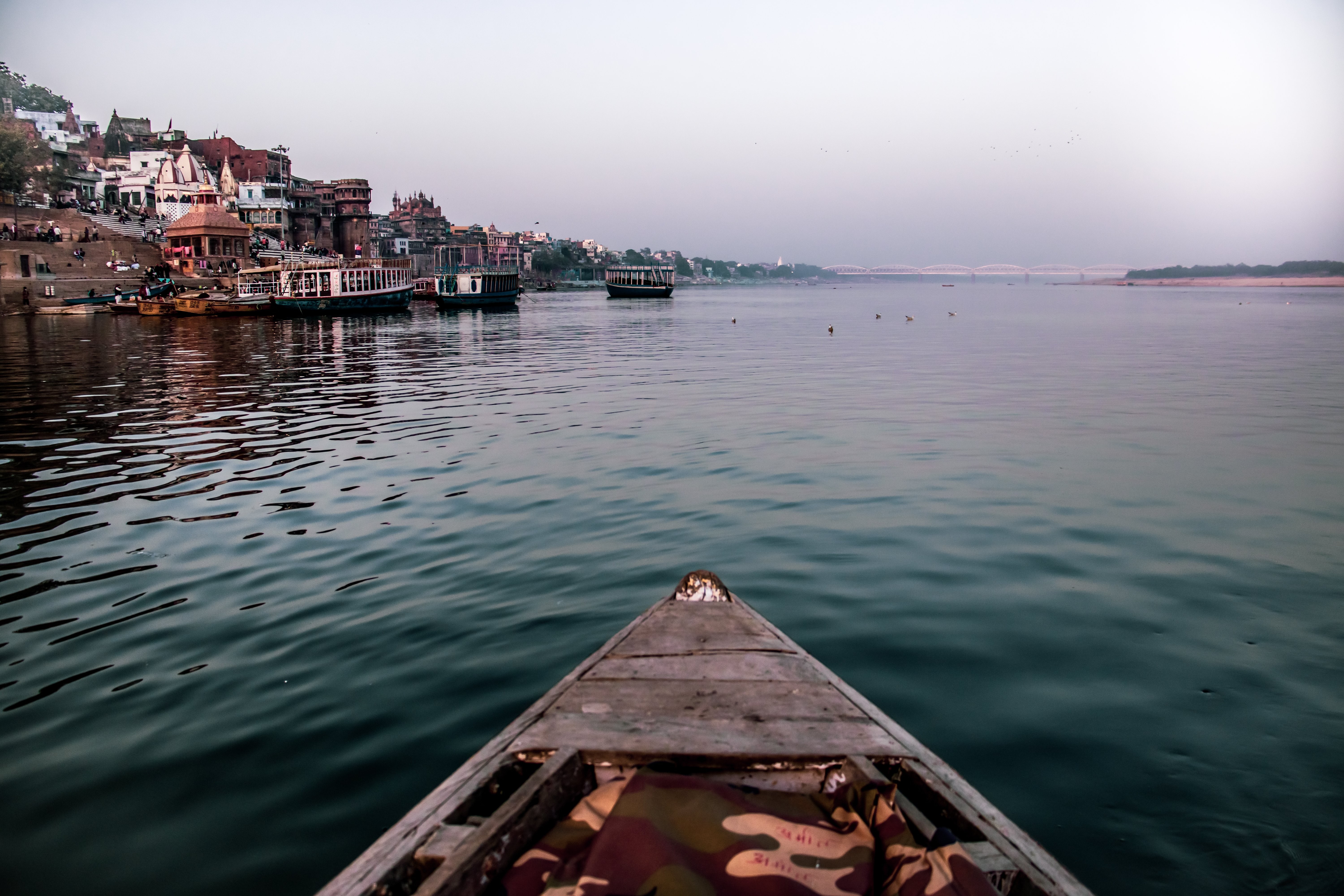 Ujung Perahu Di Atas Air Biru Dengan Kota Terdekat Foto 