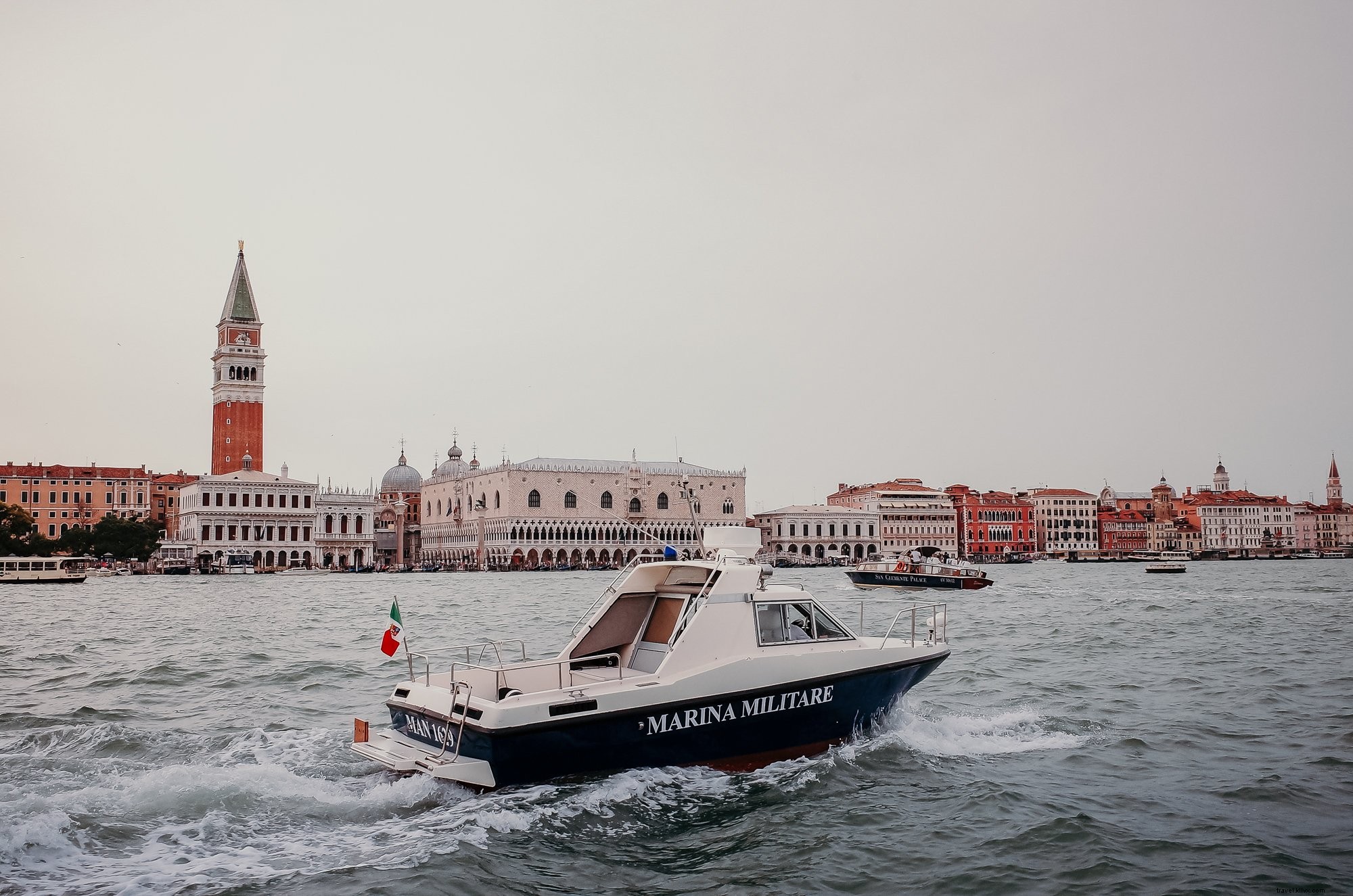 Un barco sobre agua ondulada con edificios en la distancia Foto 