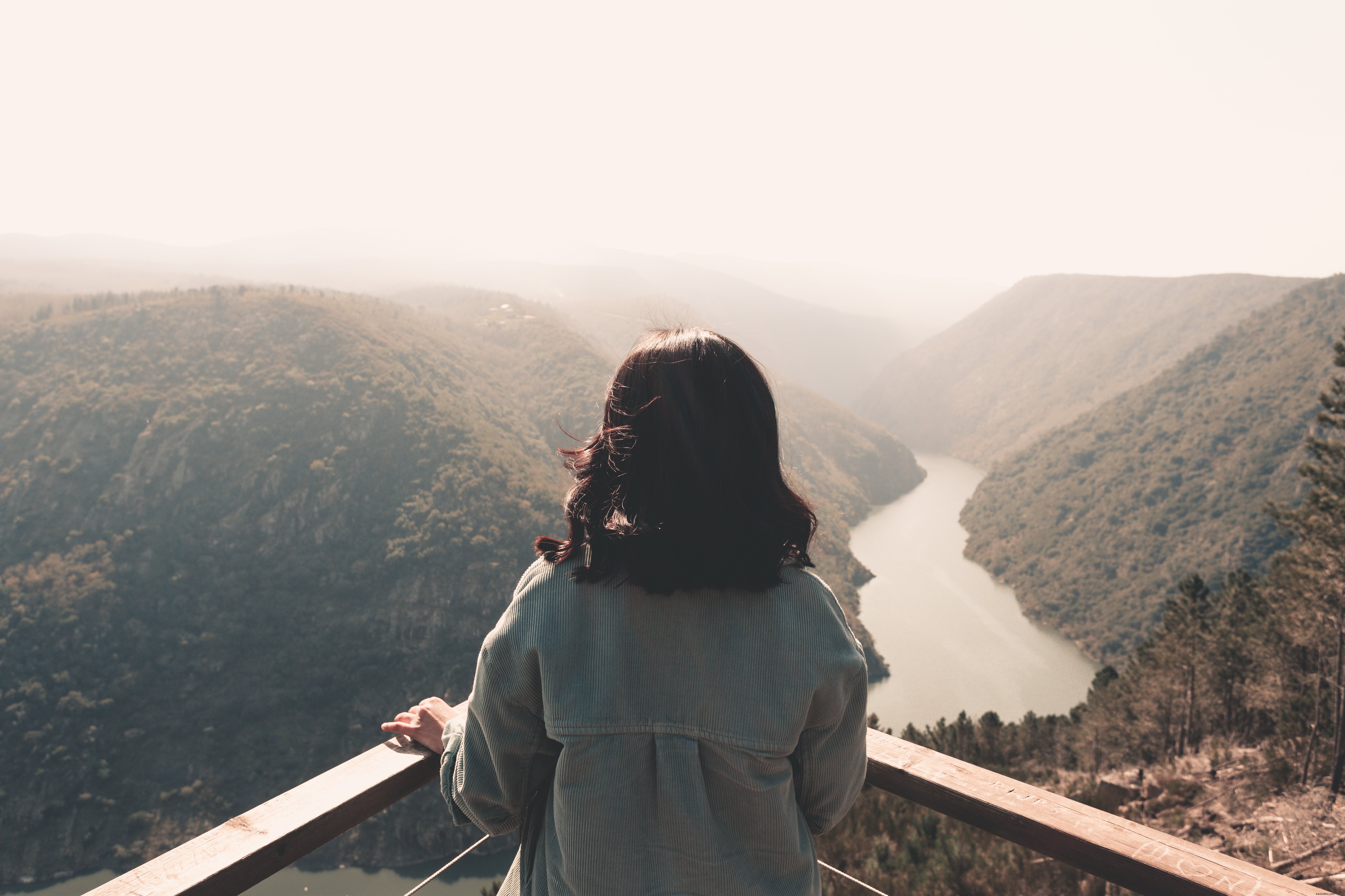 Uma pessoa em pé em um canto, tirando uma foto da vista da floresta 