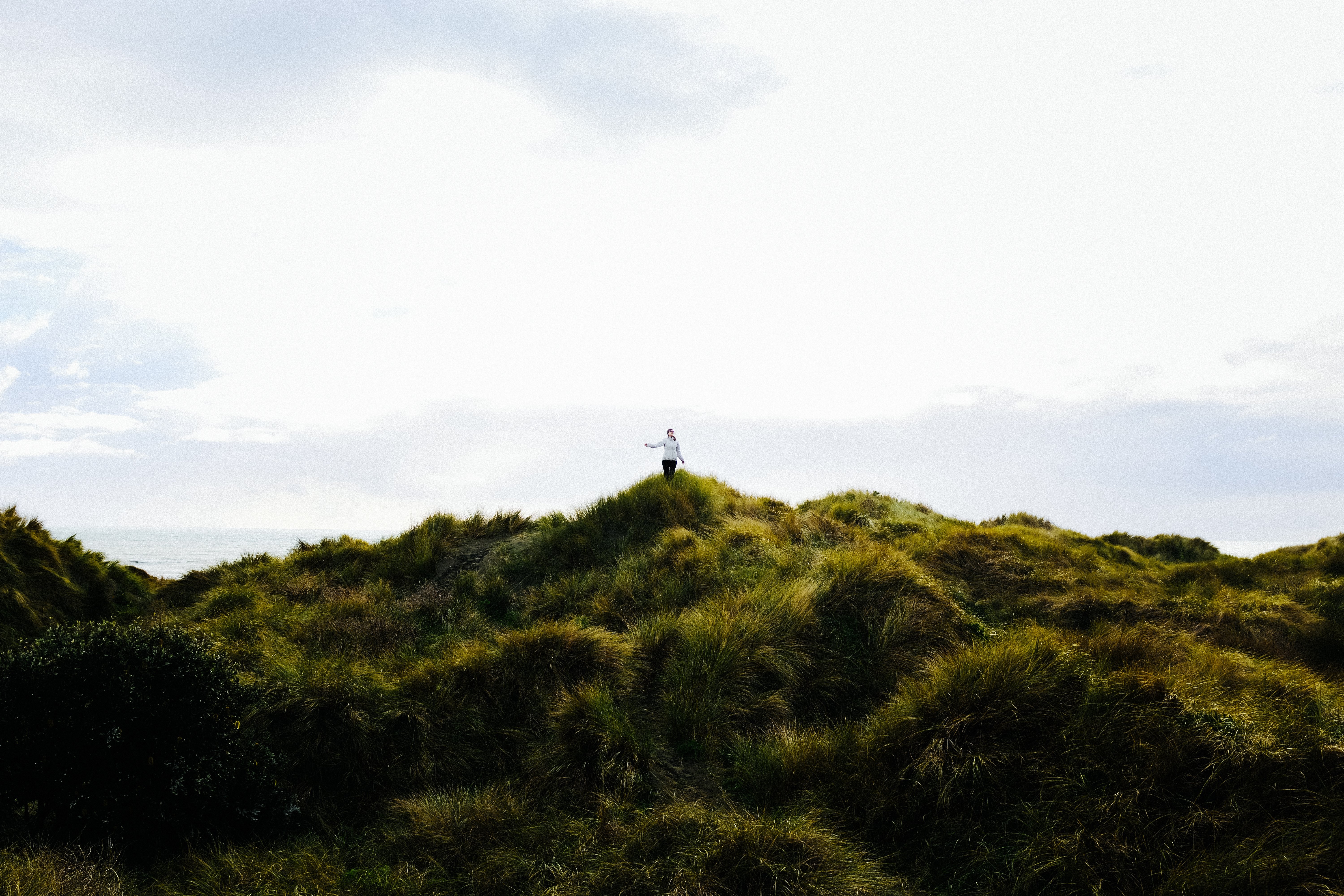 Foto de mulher caminhando pelas dunas gramíneas 