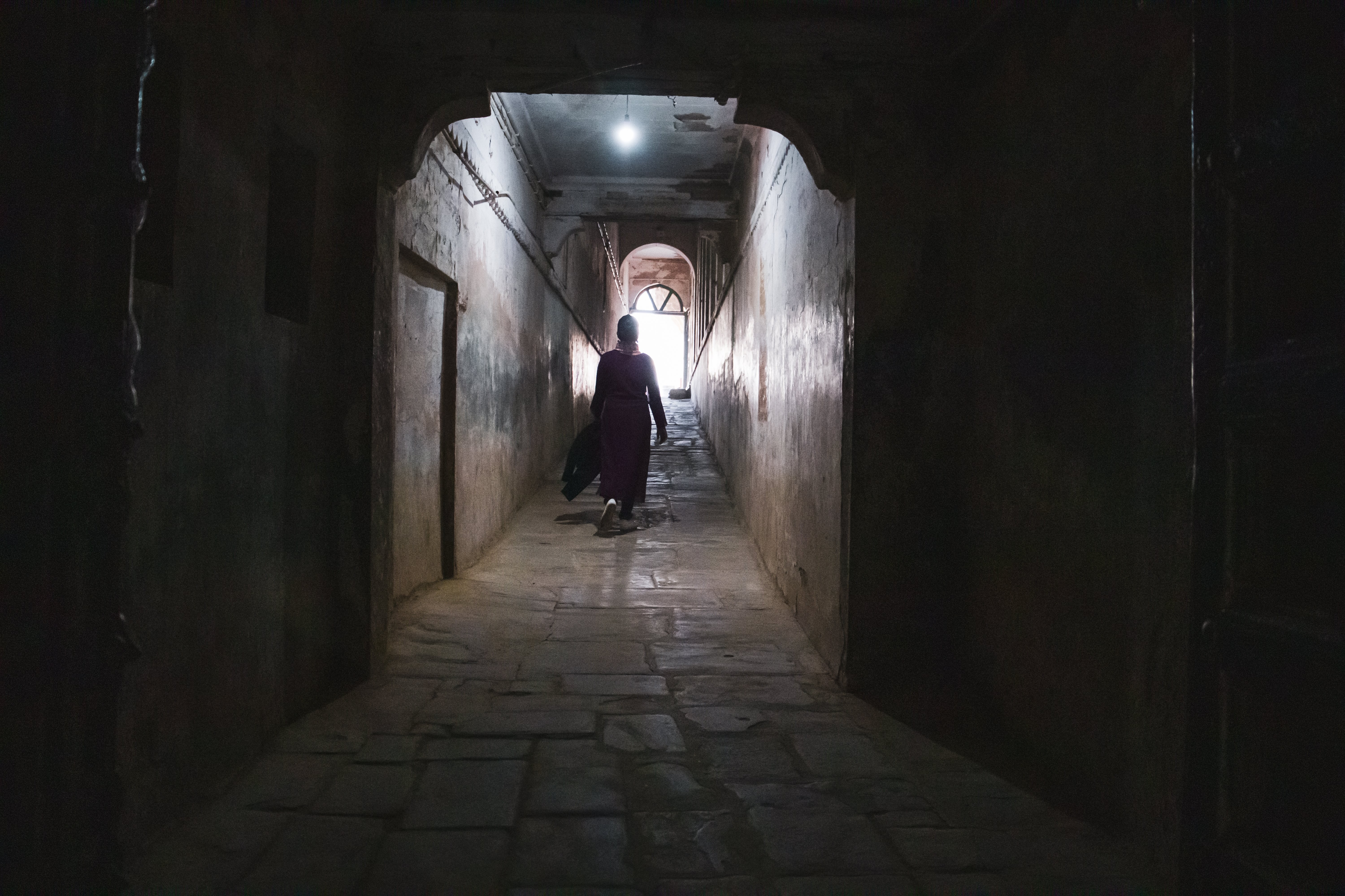 Foto de uma pessoa com a silhueta caminhando em um túnel 