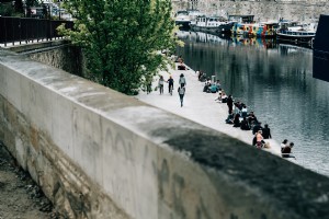 座っている人とボートが横に並んでいる運河写真 