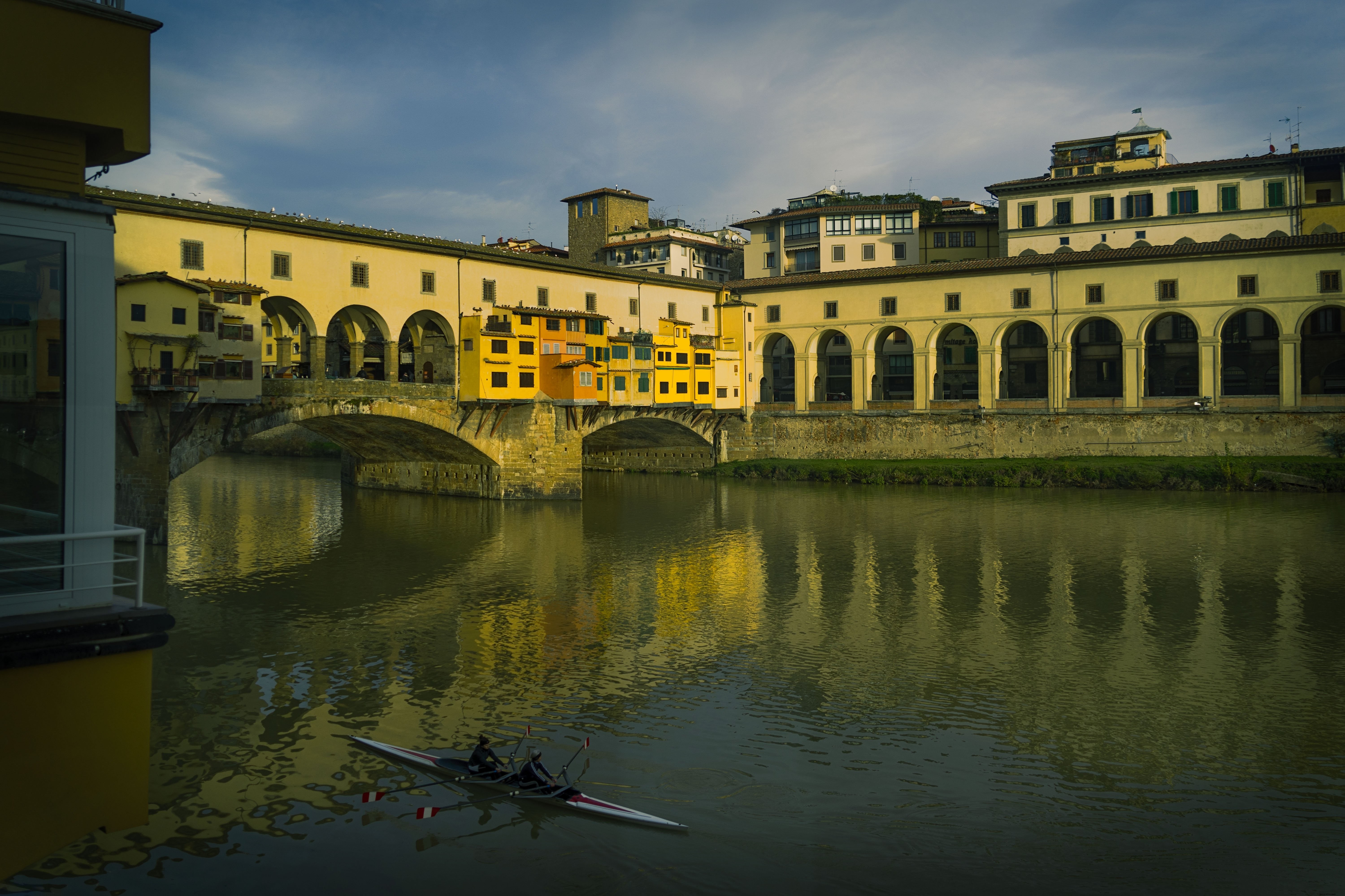 Un puente sobre un río con edificios amarillos que lo recubren Foto 