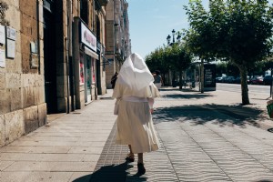 Una monja con un hábito blanco pasea por un paseo peatonal soleado Foto 