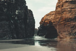 潮が岩の間の海岸に転がる写真 